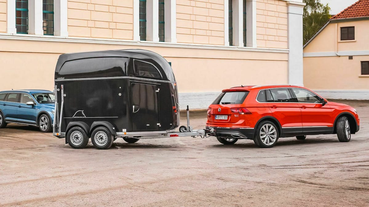 Ein roter VW Tiguan rangiert mit einem Pferdeanhänger.