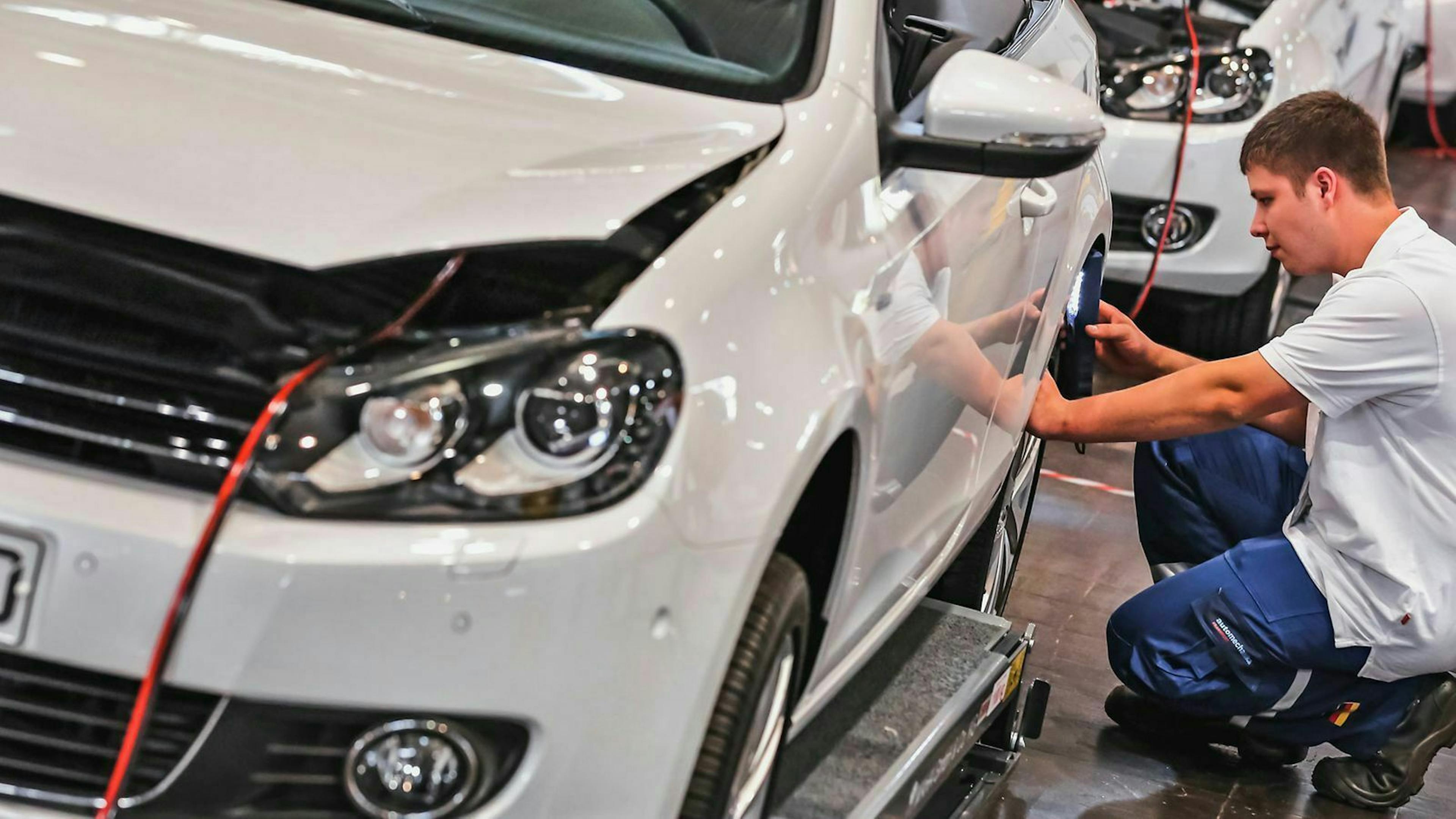 Ein Mechaniker arbeitet an einem weißen Golf Cabrio. 