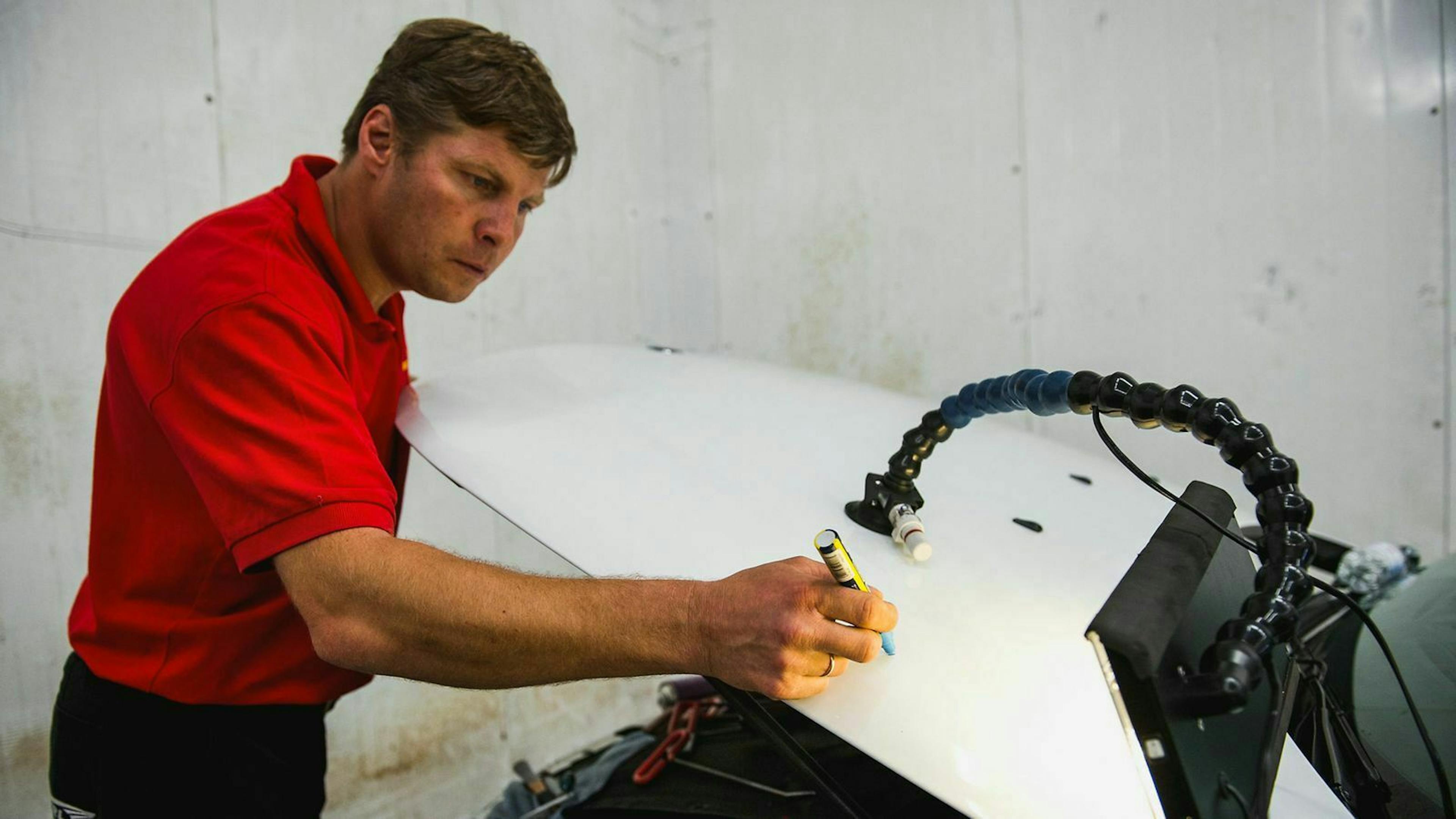 In Werkstätten werden die Dellen, die die Hagelkörner verursacht haben, meist zunächst markiert.