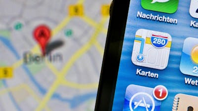 In Nahaufnahme ist das app-Symbol von Apples Kartendienst zu sehen während im Hintergrund eine Google Maps Karte geöffnet ist.