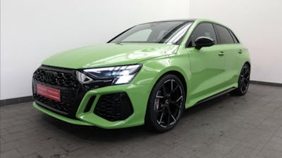 Ein grüner Audi RS3 Sportback steht vor einer weißen Wand