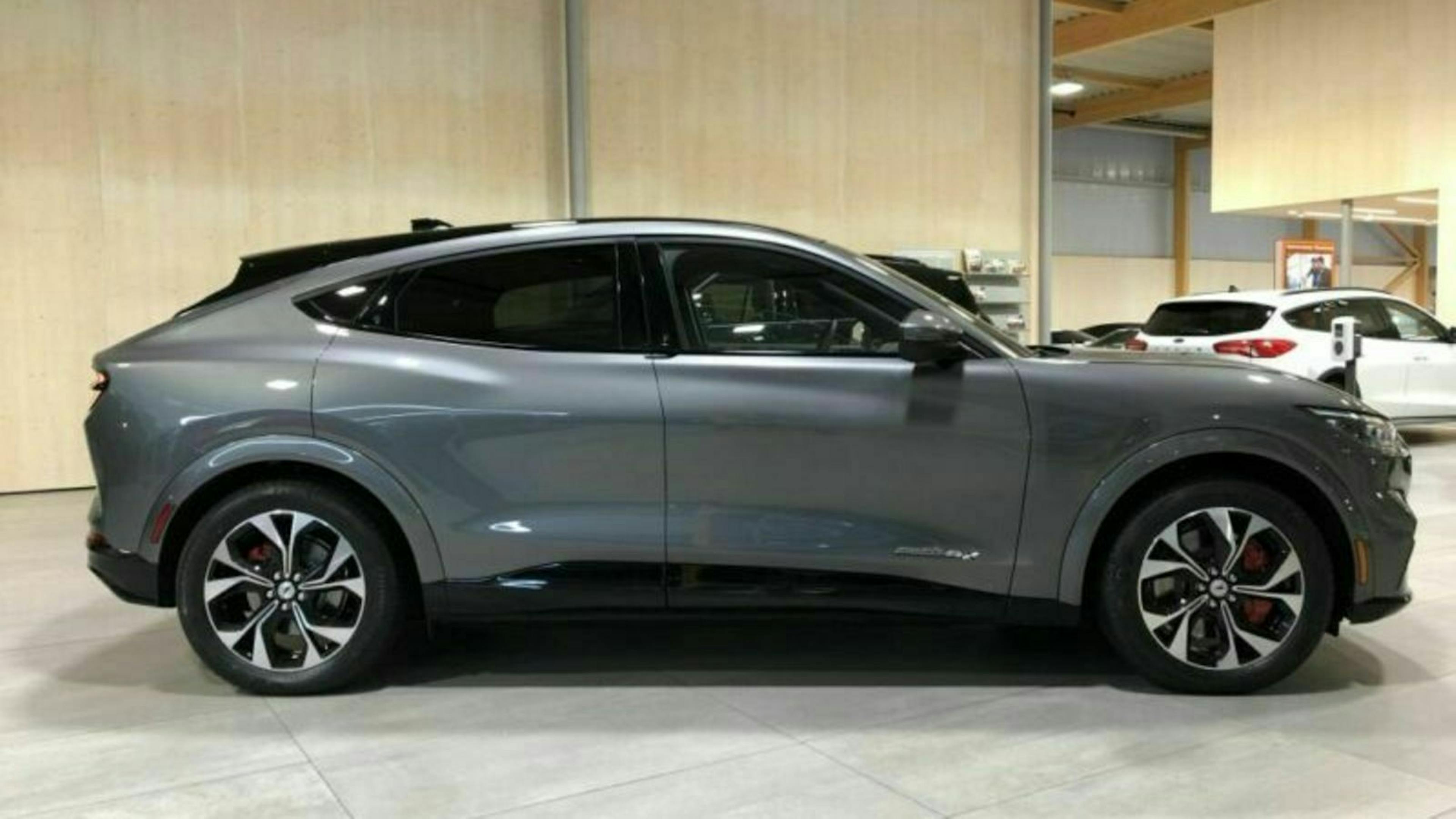 Graues SUV mit sportlichem Design steht in einem modernen Autohaus. Im Hintergrund sind andere Fahrzeuge sichtbar.