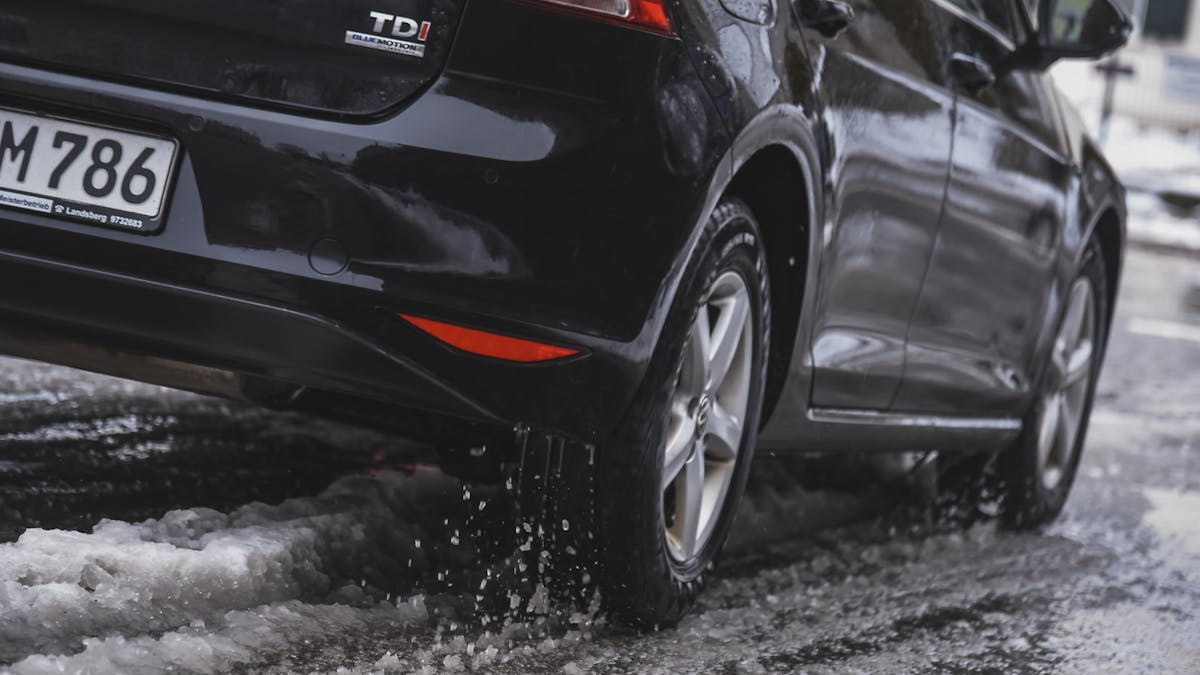 Ein frisch gewaschener VW Golf fährt über eine Straße, die von Schneematsch bedeckt ist.