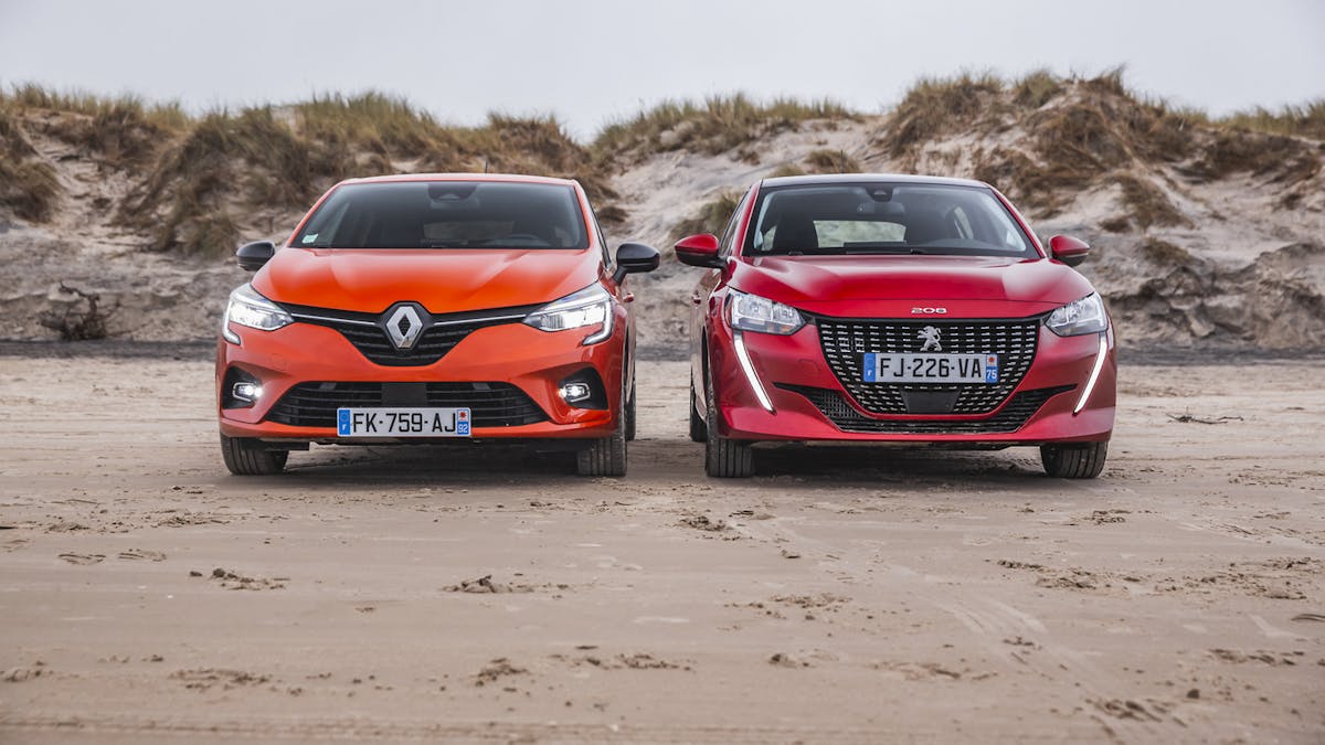 Peugeot 208 und Renault Clio vor einer Düne nebeneinander stehend am Strand