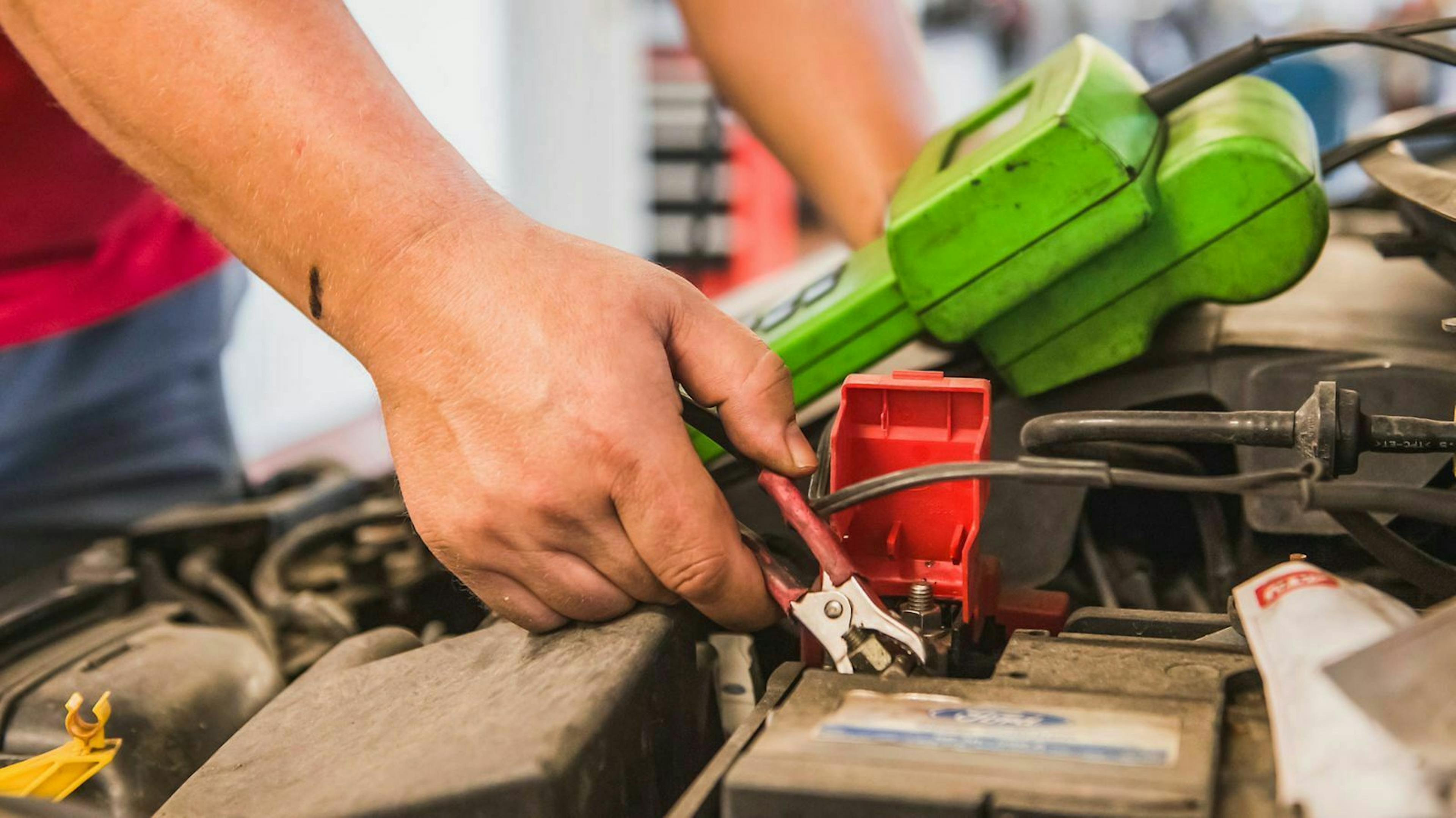 Ein Mechaniker überprüft die Spannung einer Autobatterie.