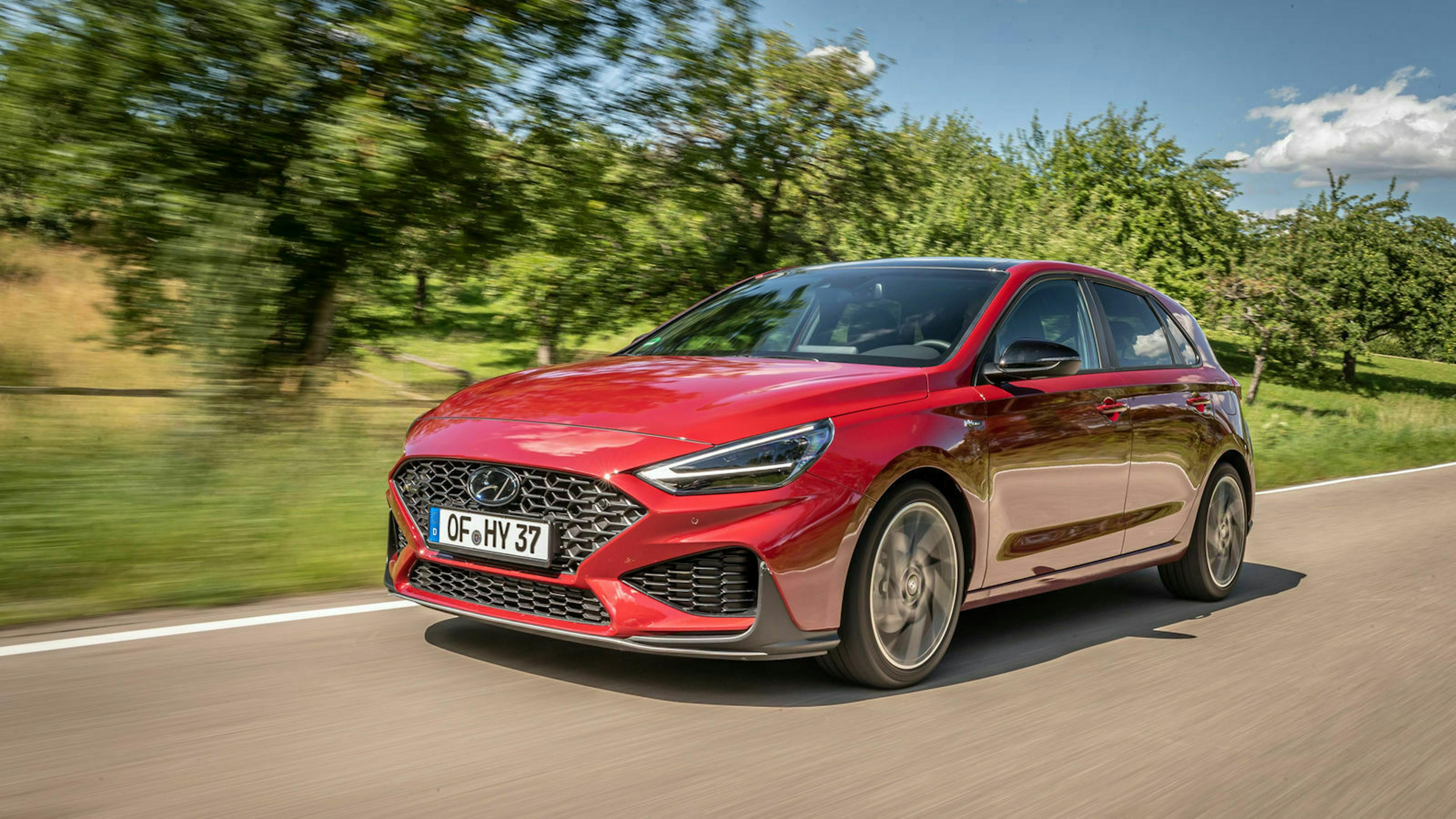 Ein roter Hyundai i30 fährt eine Landstraße entlang