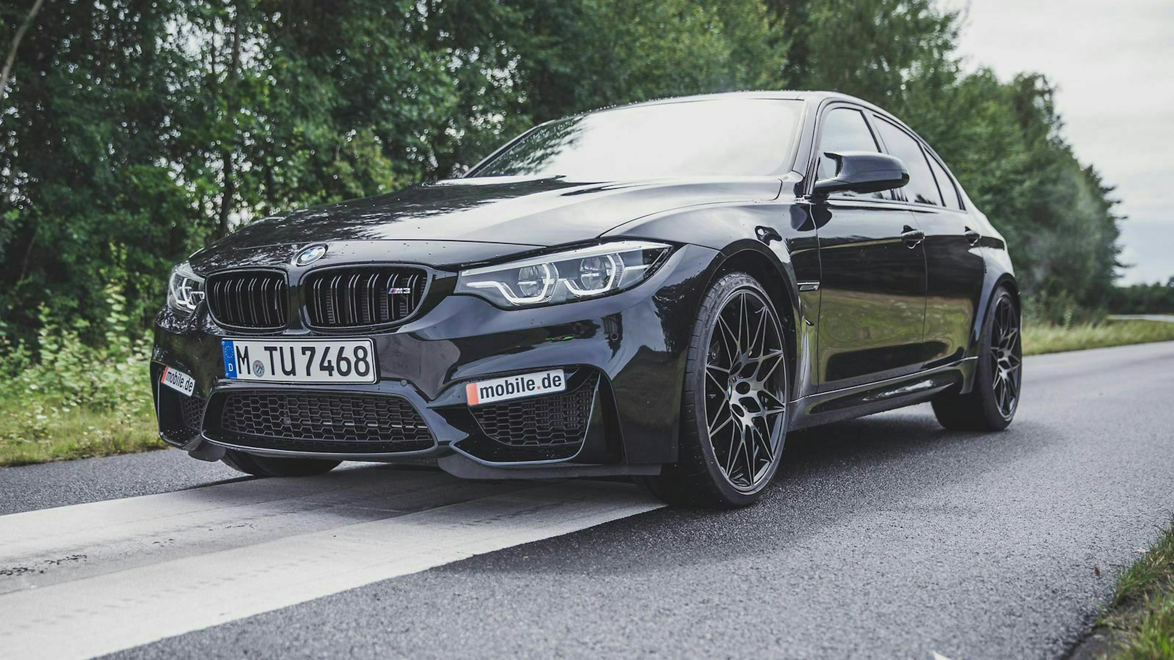 Schwarzer BMW M3 auf Nebenstraße - Totalansicht 