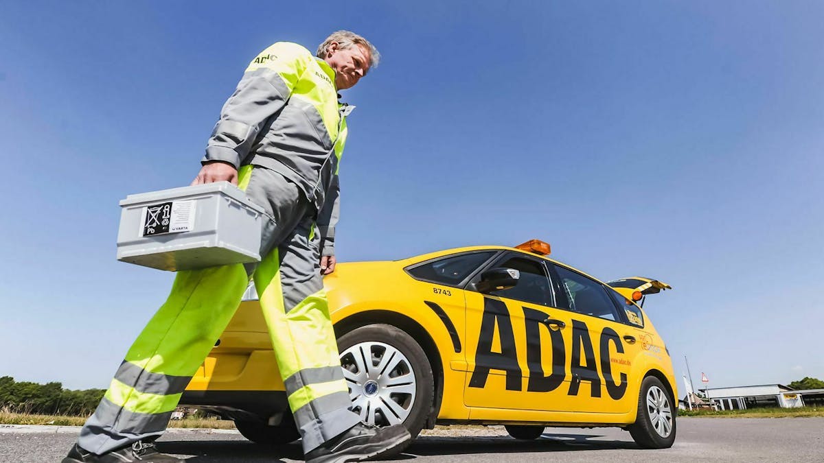 Ein ADAC-Mitarbeiter trägt eine neue Autobatterie vor seinem Einsatzfahrzeug her.