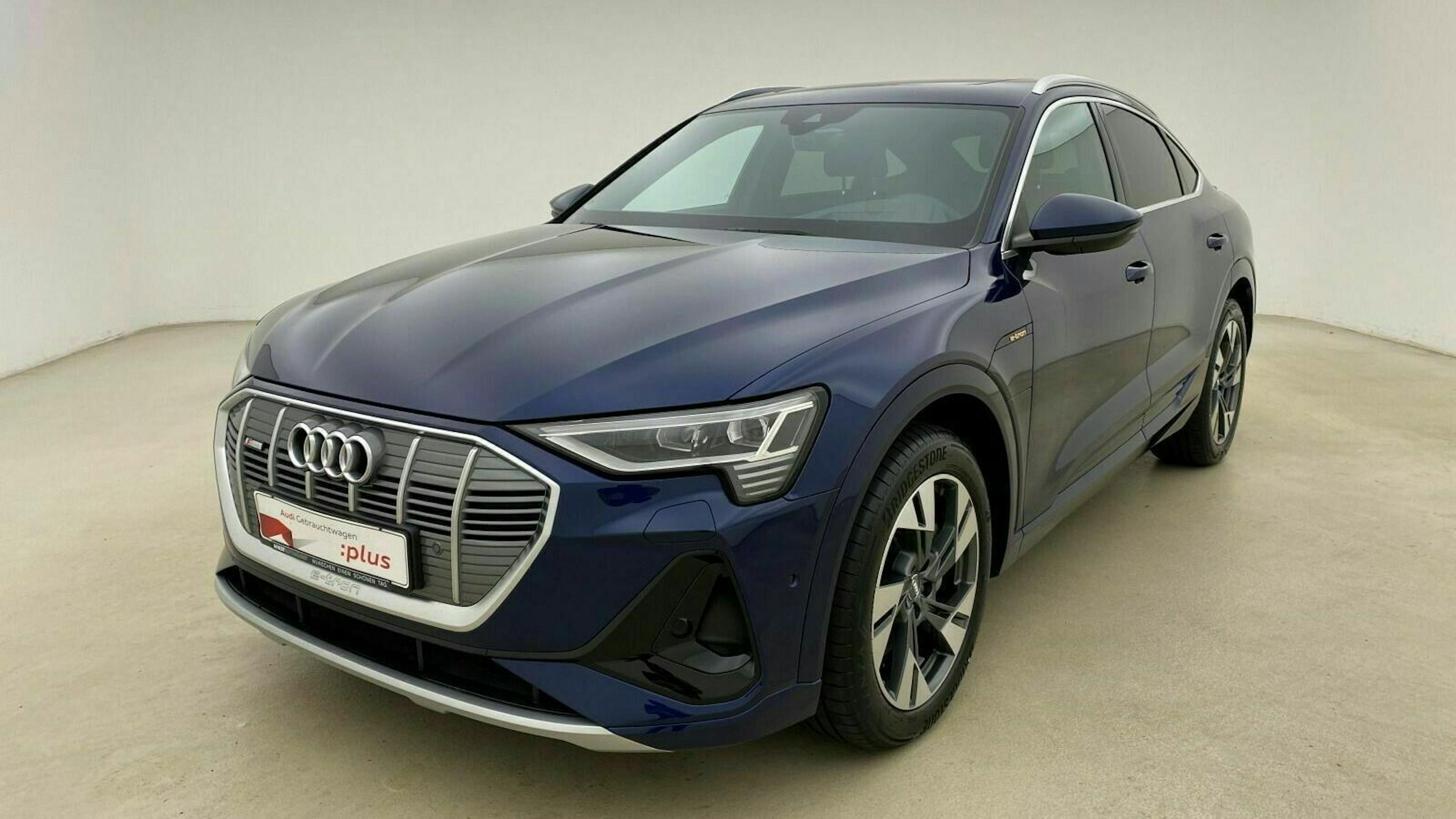 Ein blauer Audi e-tron GT steht in einem beigefarbenen Raum