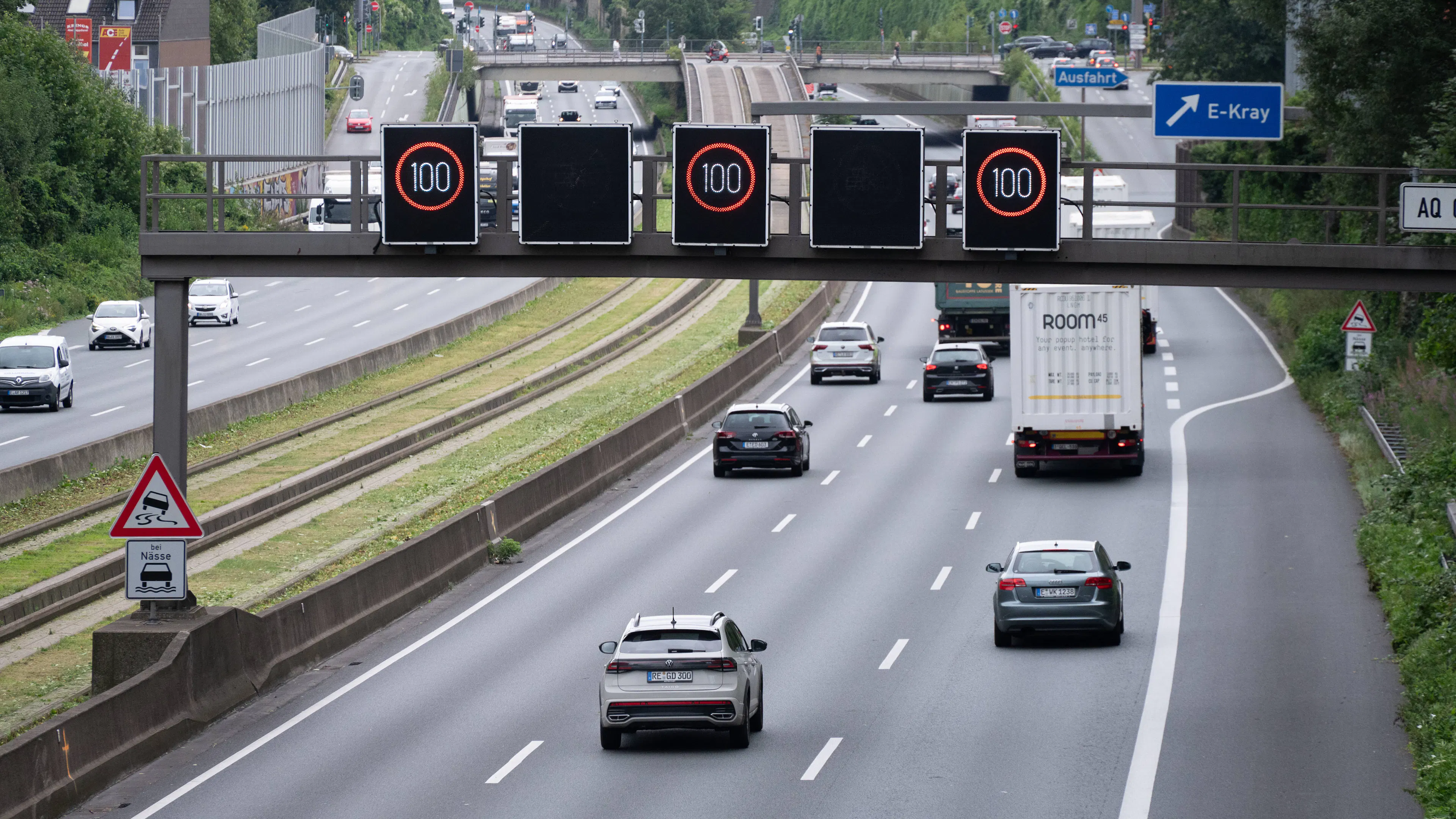Pkw und Lkw auf der Autobahn A 40 bei Essen, Schilderbrücke mit Geschwindigkeitsanzeige Tempo 100.