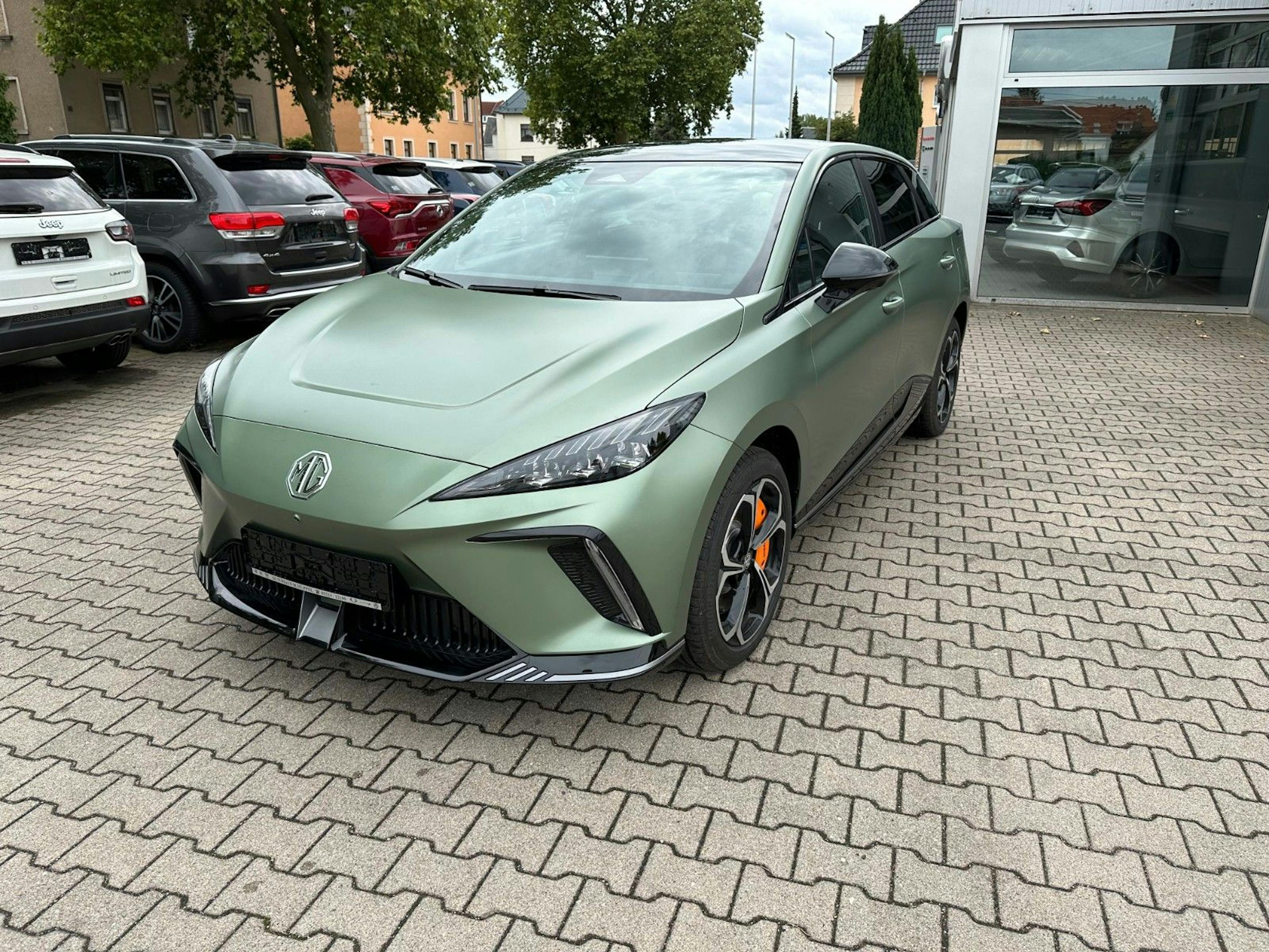 Ein grüner MG4 Electric steht auf dem Hof eines Autohauses.