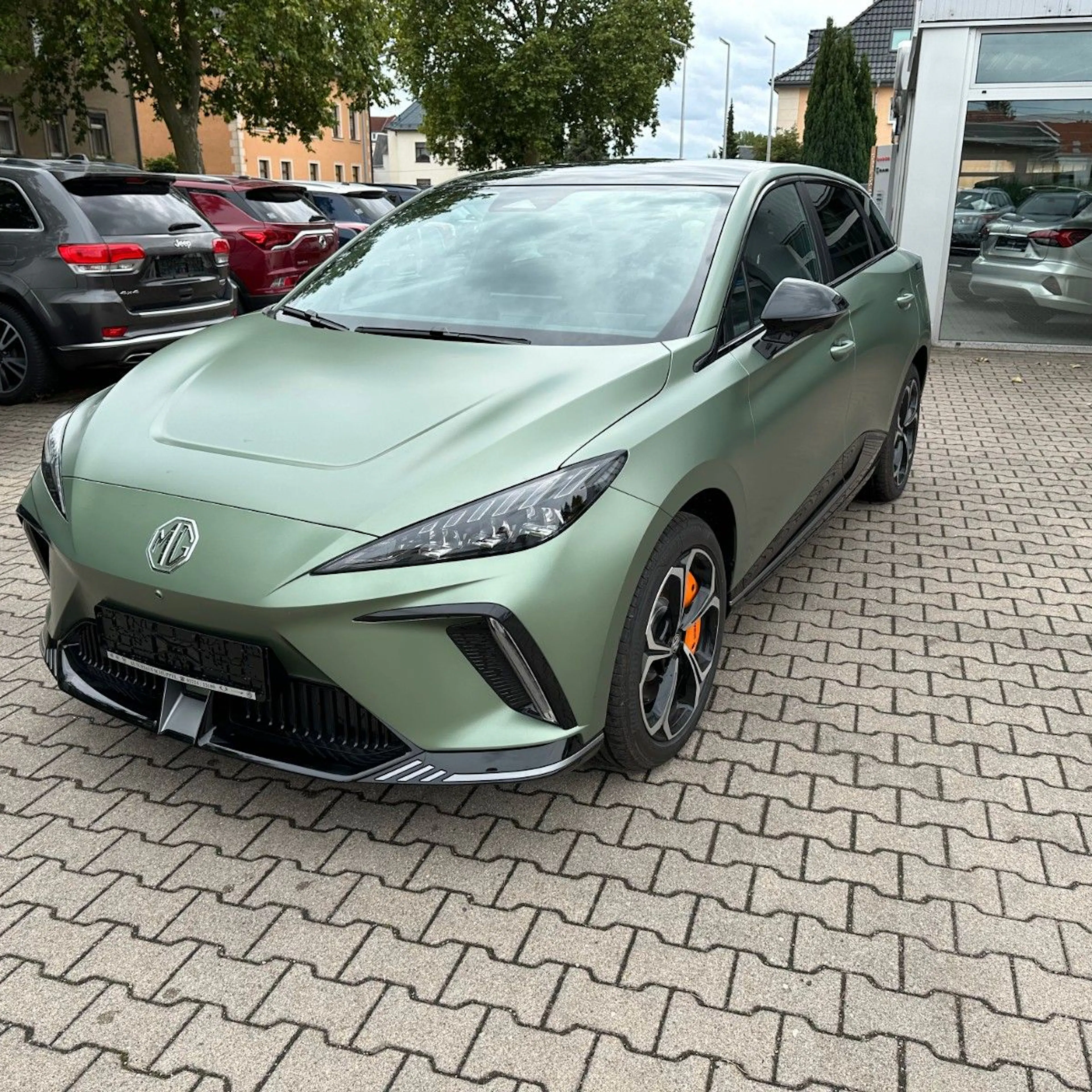 Ein grüner MG4 Electric steht auf dem Hof eines Autohauses.
