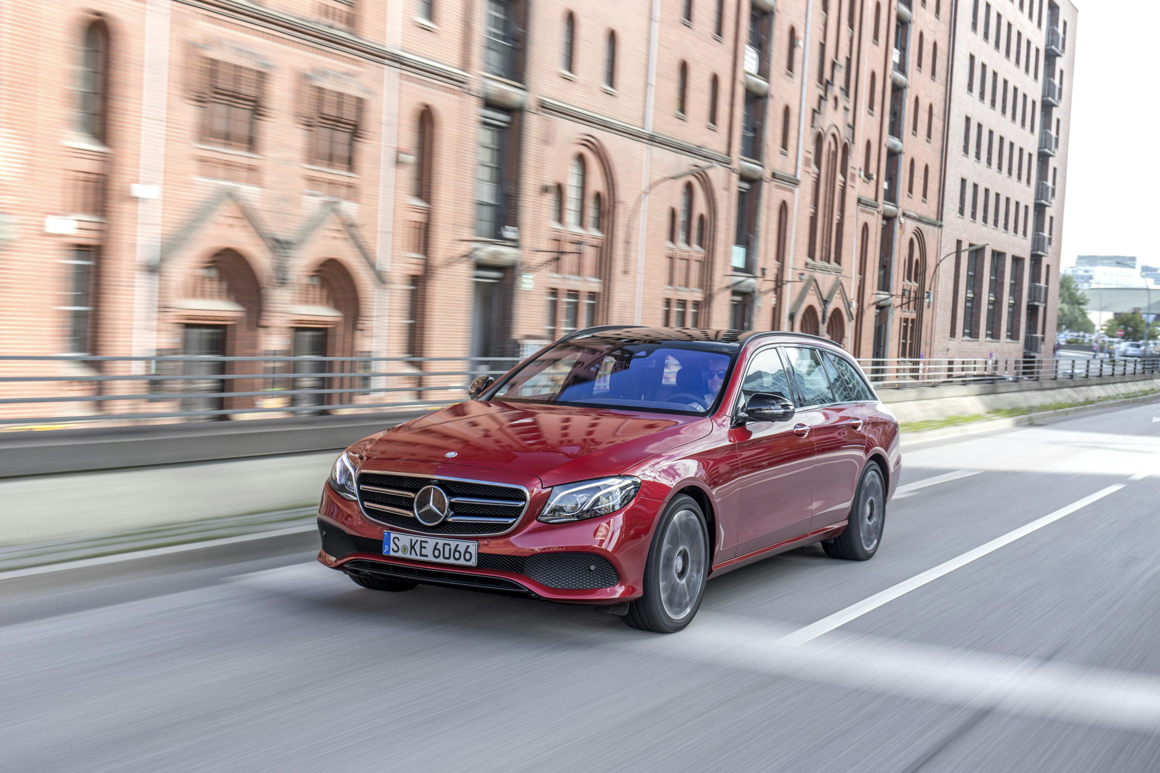 Ein rotes Mercedes E-Klasse T-Modell fährt an einem alten Lagerhaus vorbei.