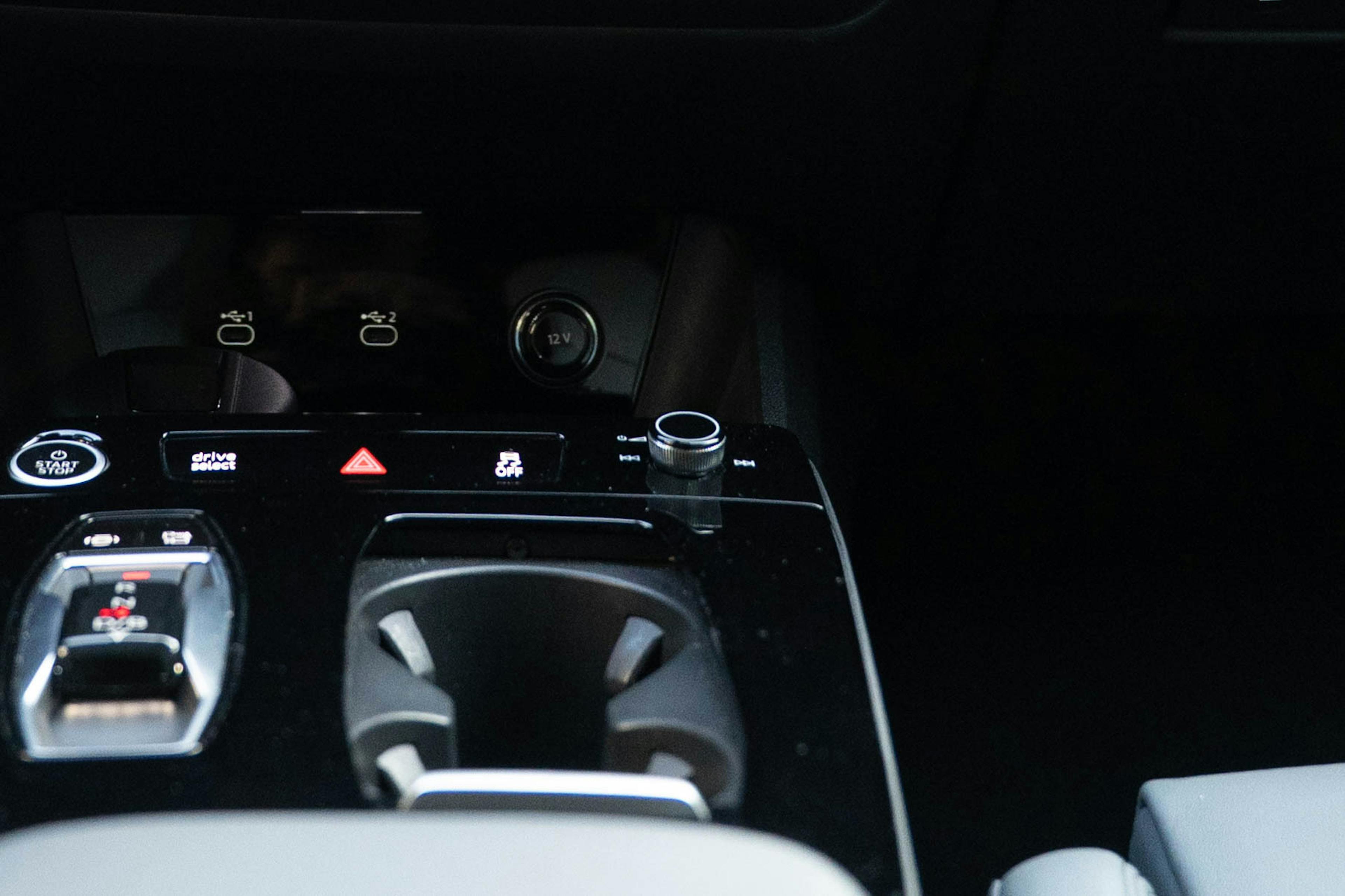 Nahaufnahme eines schwarzen Drehreglers in einem Auto, umgeben von Bedienelementen für das Infotainmentsystem.