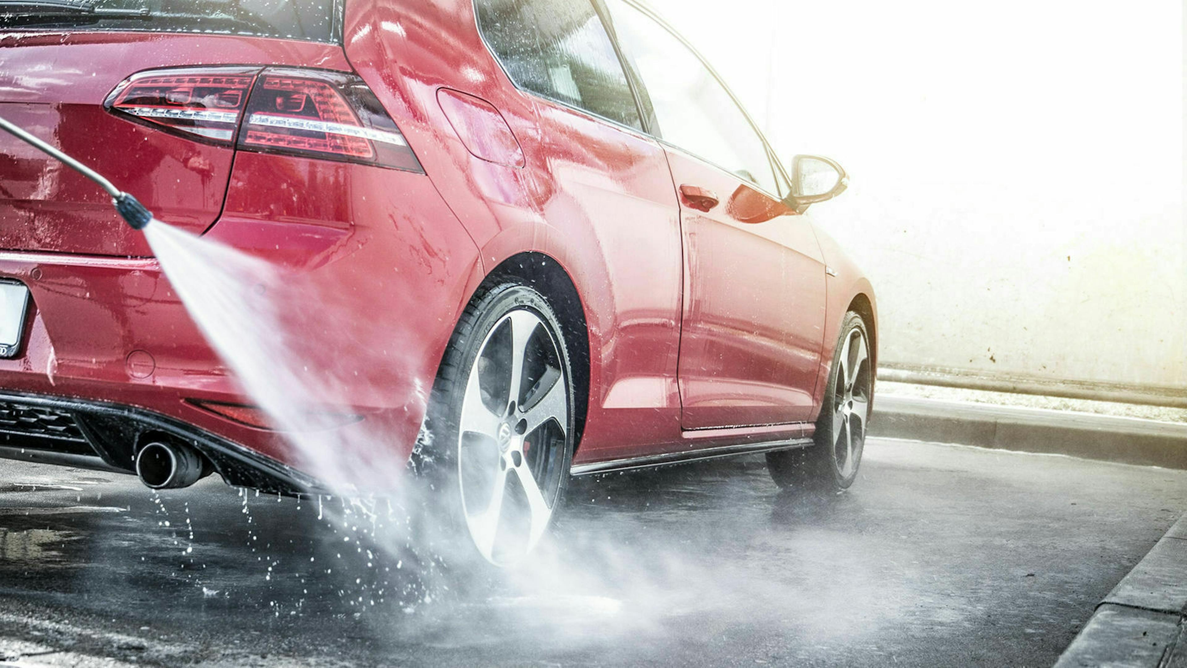 Ein roter VW Golf wird in einer SB-Waschbox abgespritzt