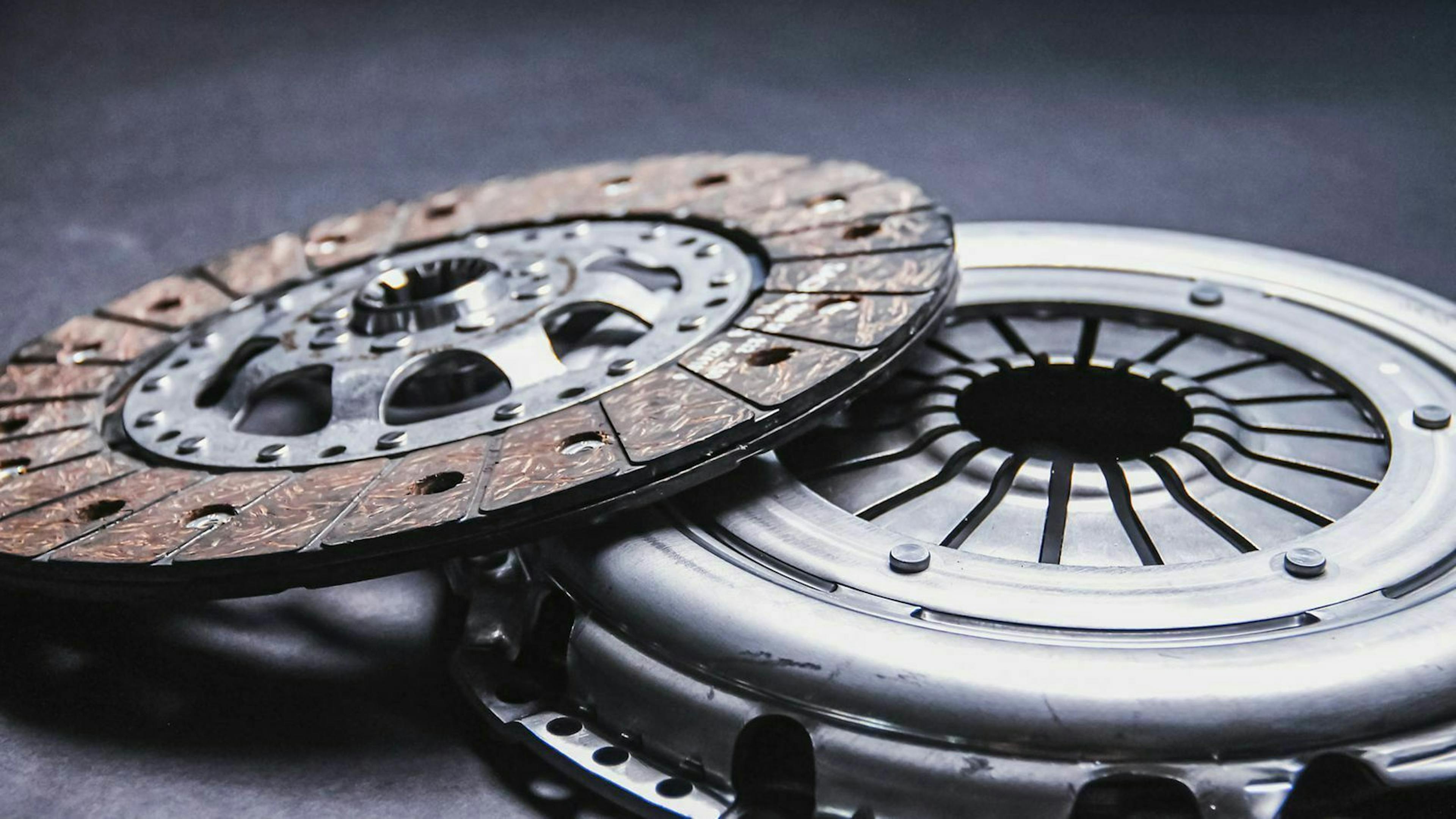 Kupplungskorb und Kupplungsscheibe von ZF liegen auf dunklem Grund.