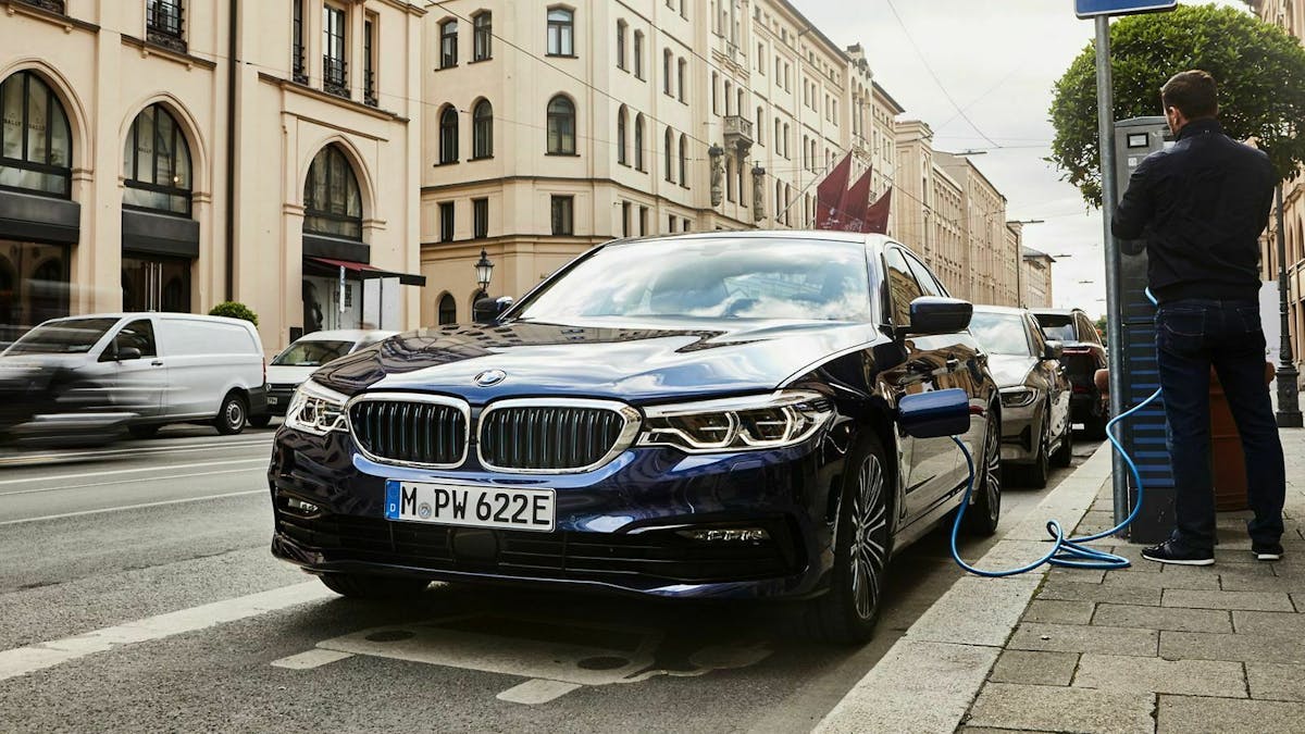 Dunkler BMW 530e parkt am Straßenrand neben einer Ladesäule