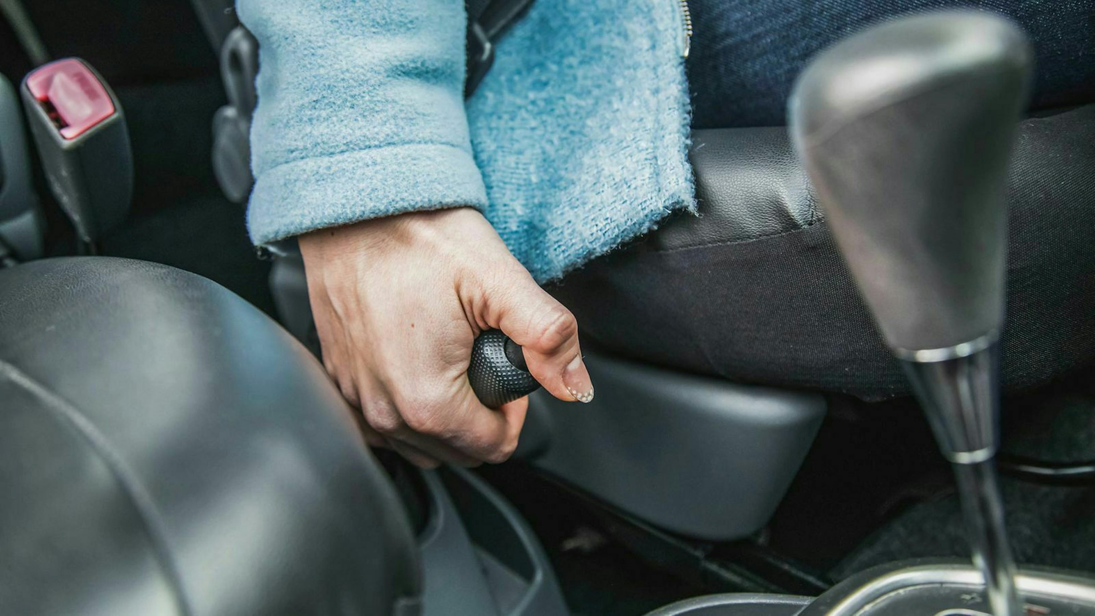 Eine Frau zieht den Handbremshebel eines Autos.