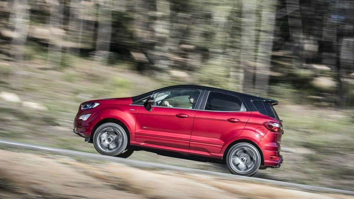 Ford Ecosport fahrend auf einer Landstraße. Im Hintergrund ist ein Wald zu sehen