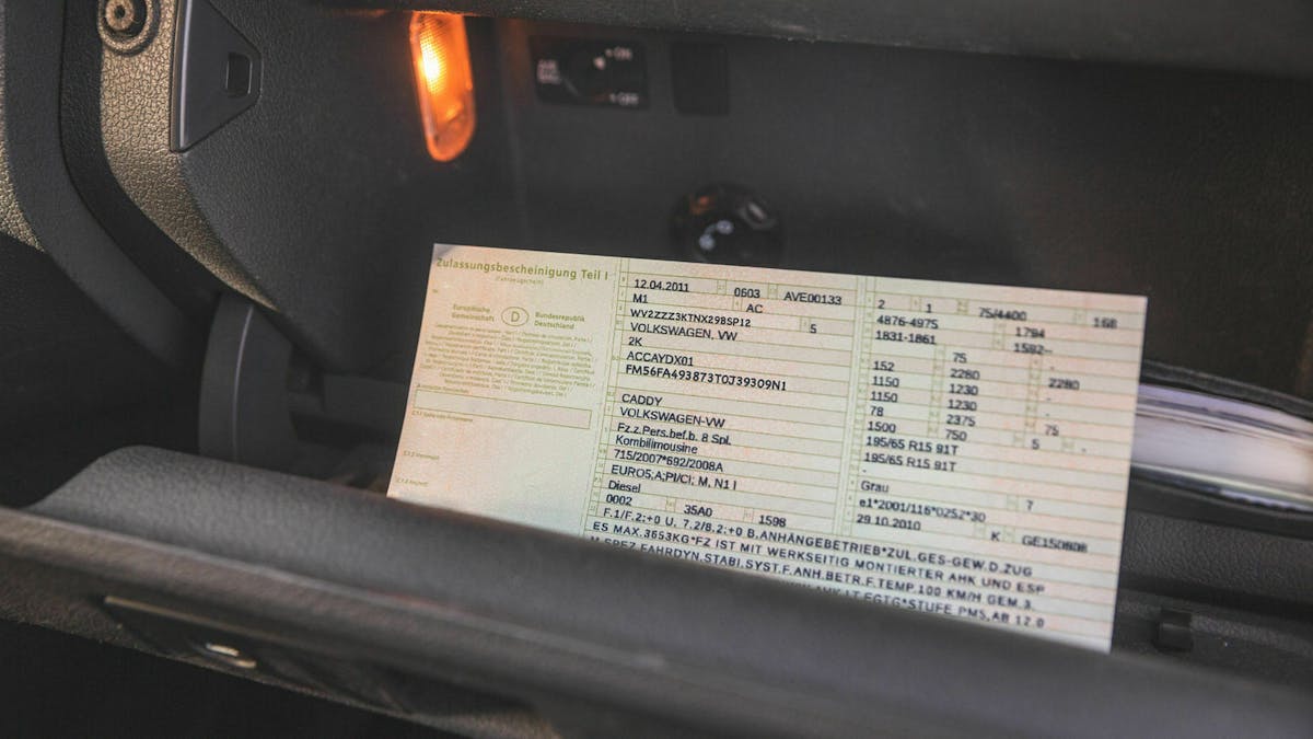 Ein Fahrzeugschein wird aus dem Handschuhfach im Innenraum des Autos geholt