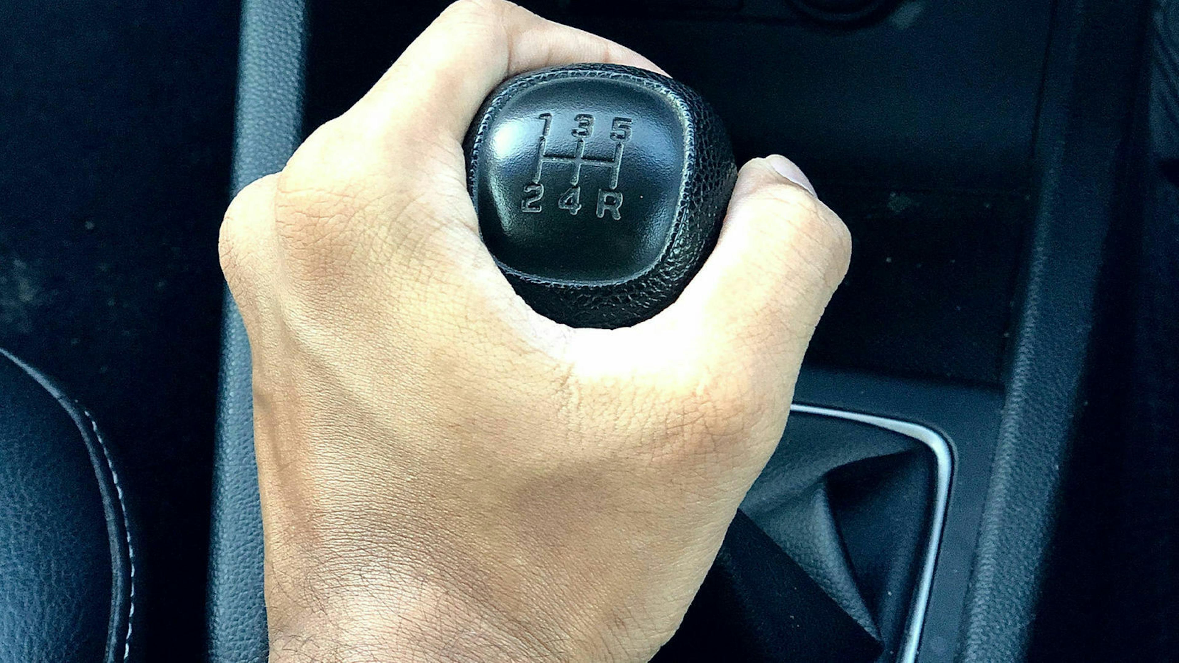 Nahaufnahme einer Hand, die den Schalthebel eines PKW betätigt