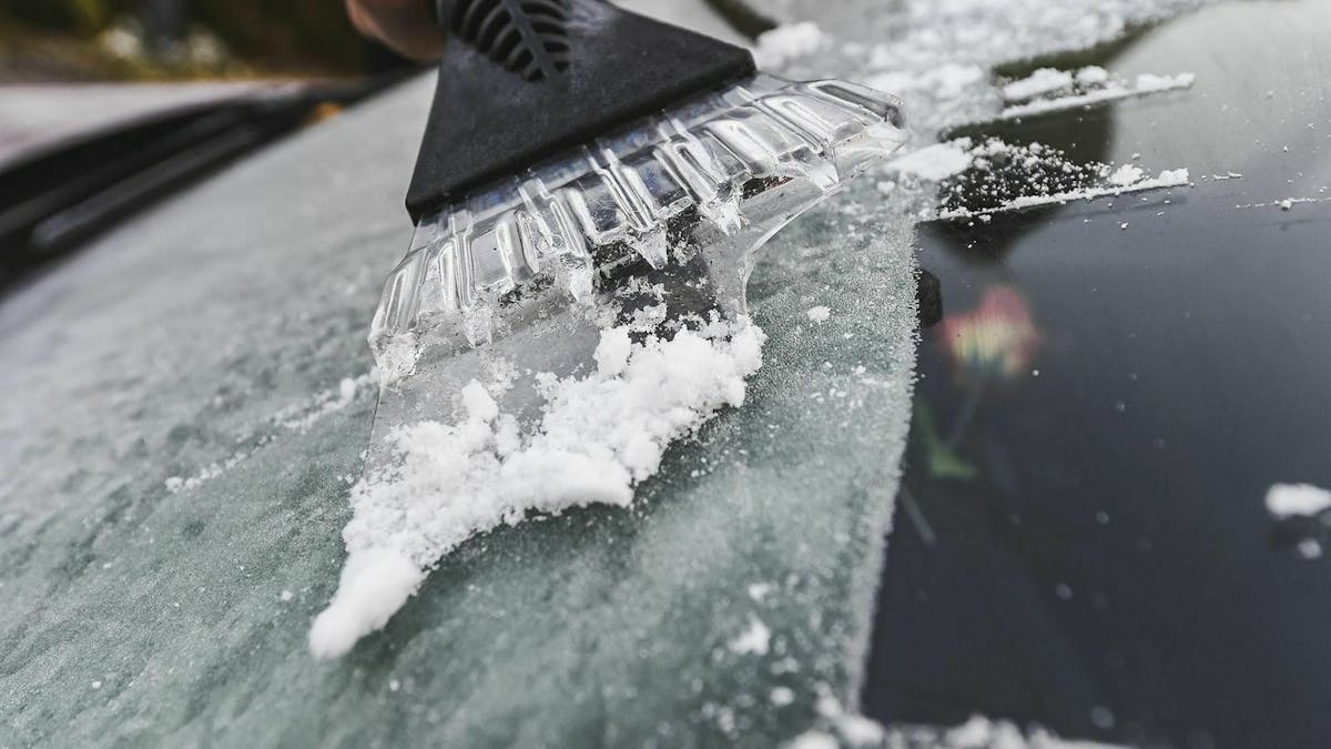 Eiskratzer an Fronstscheibe eines Autos