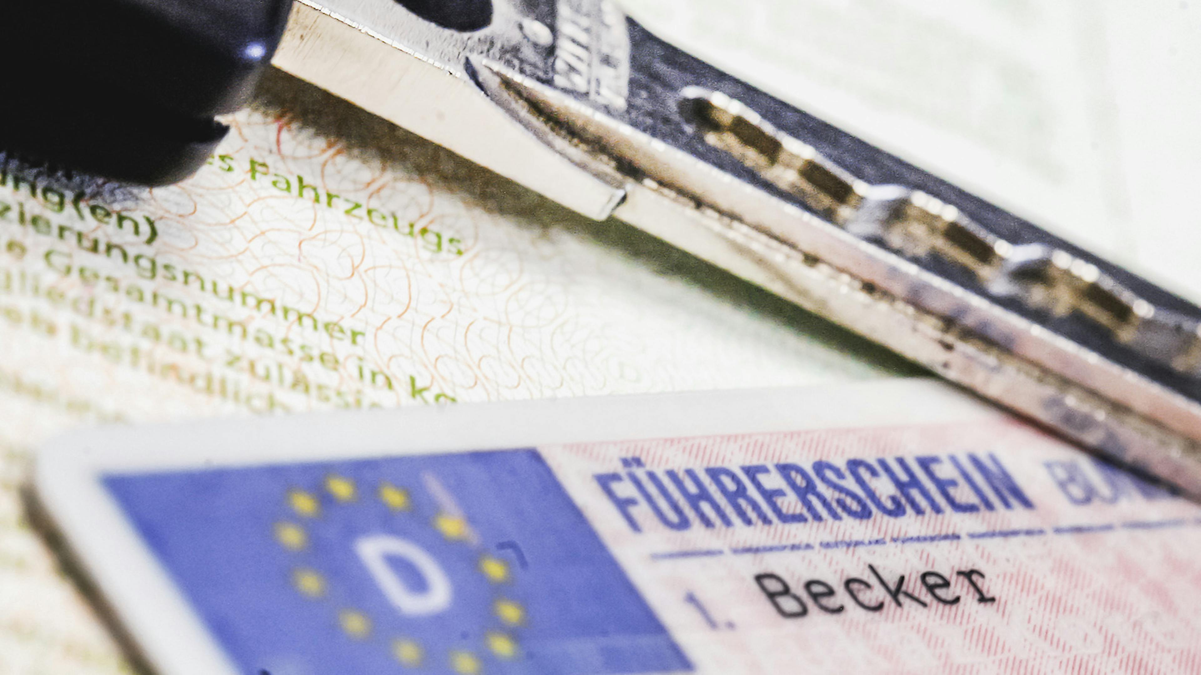 Ein neuer Führerschein im Checkkartenformat liegt auf einem alten Papierführerschein zusammen mit einem Autoschlüssel