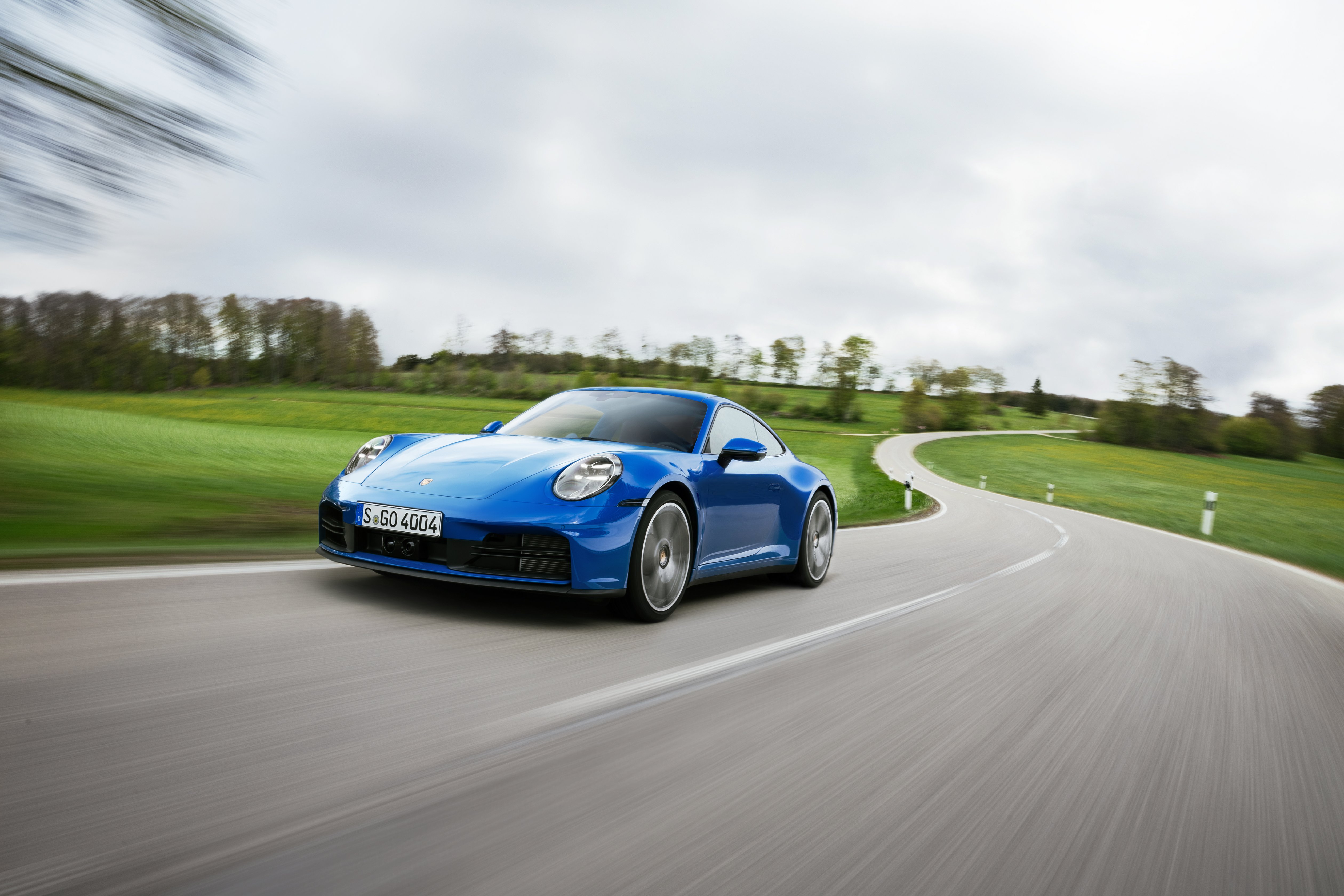 EIn blauer Porsche 911 2024 fährt auf einer Landstraße. 