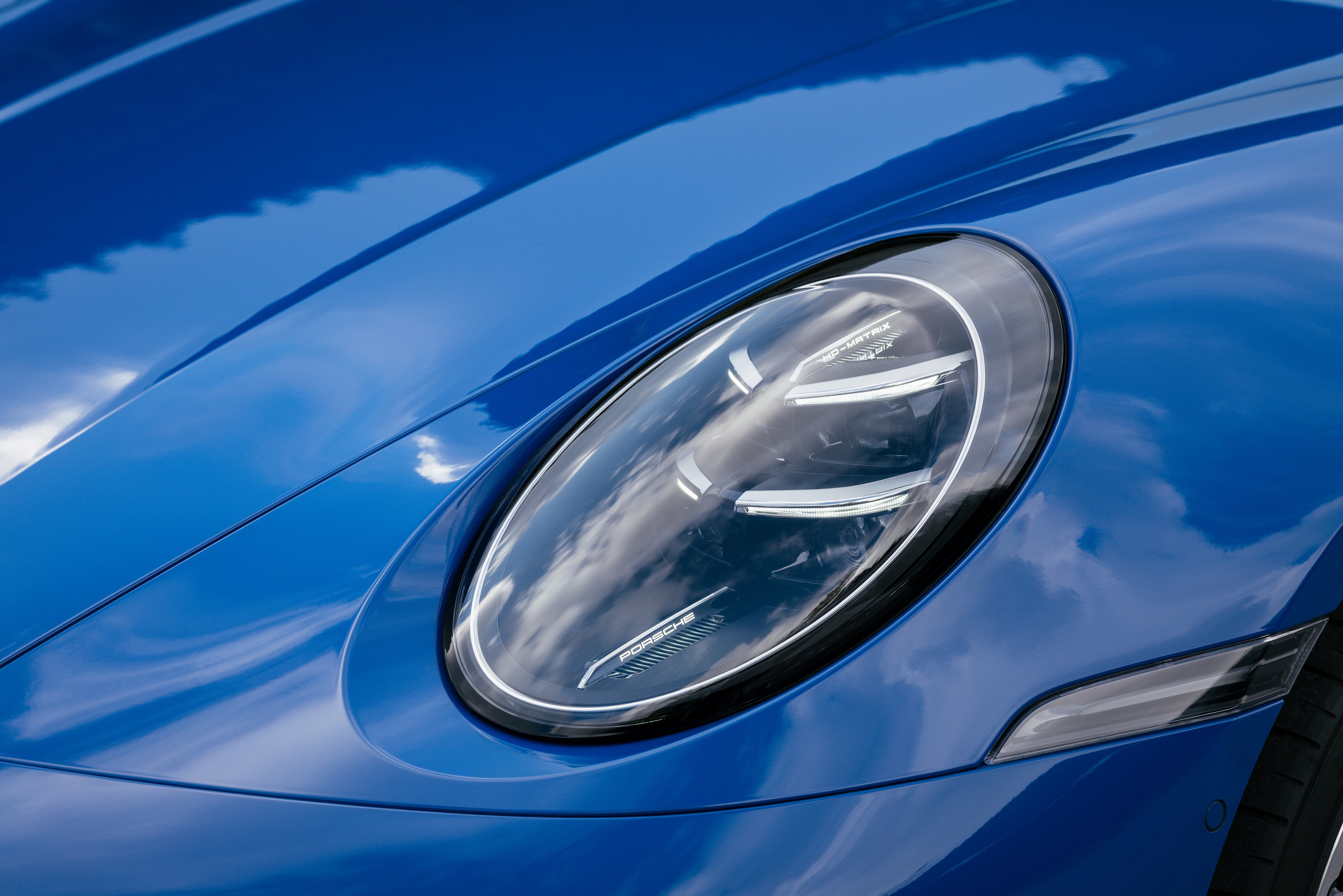 Der Scheinwerfer eines blauen Porsche 911 von 2024. 