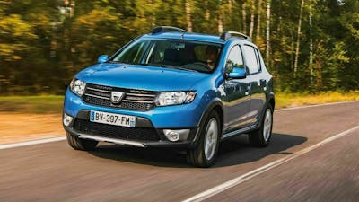 Ein blauer Dacia Sandero fährt an einem Wald vorbei