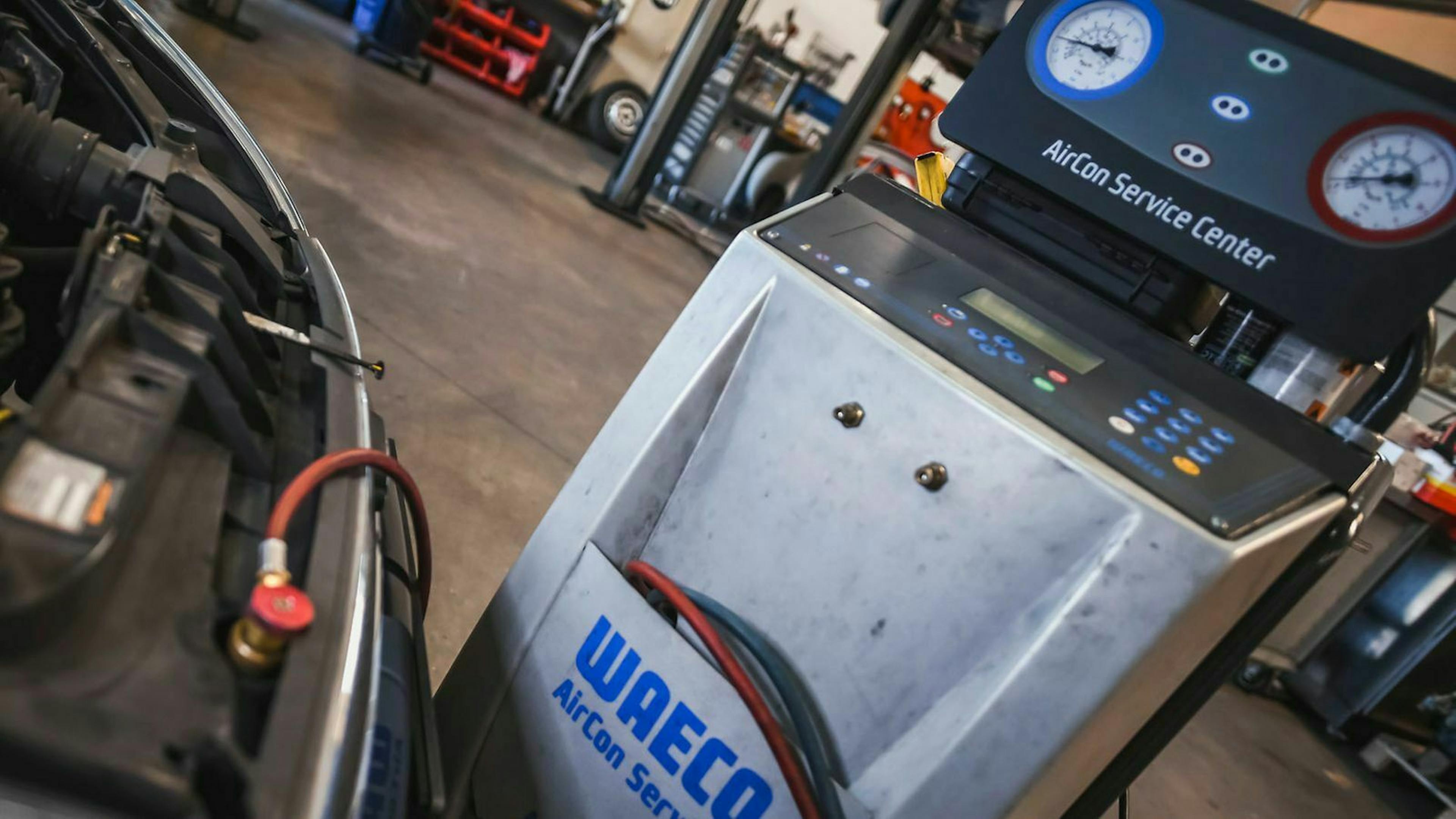 In einer Werkstatt ist ein Wartungsgerät für Klimaanlagen an ein Auto angeschlossen