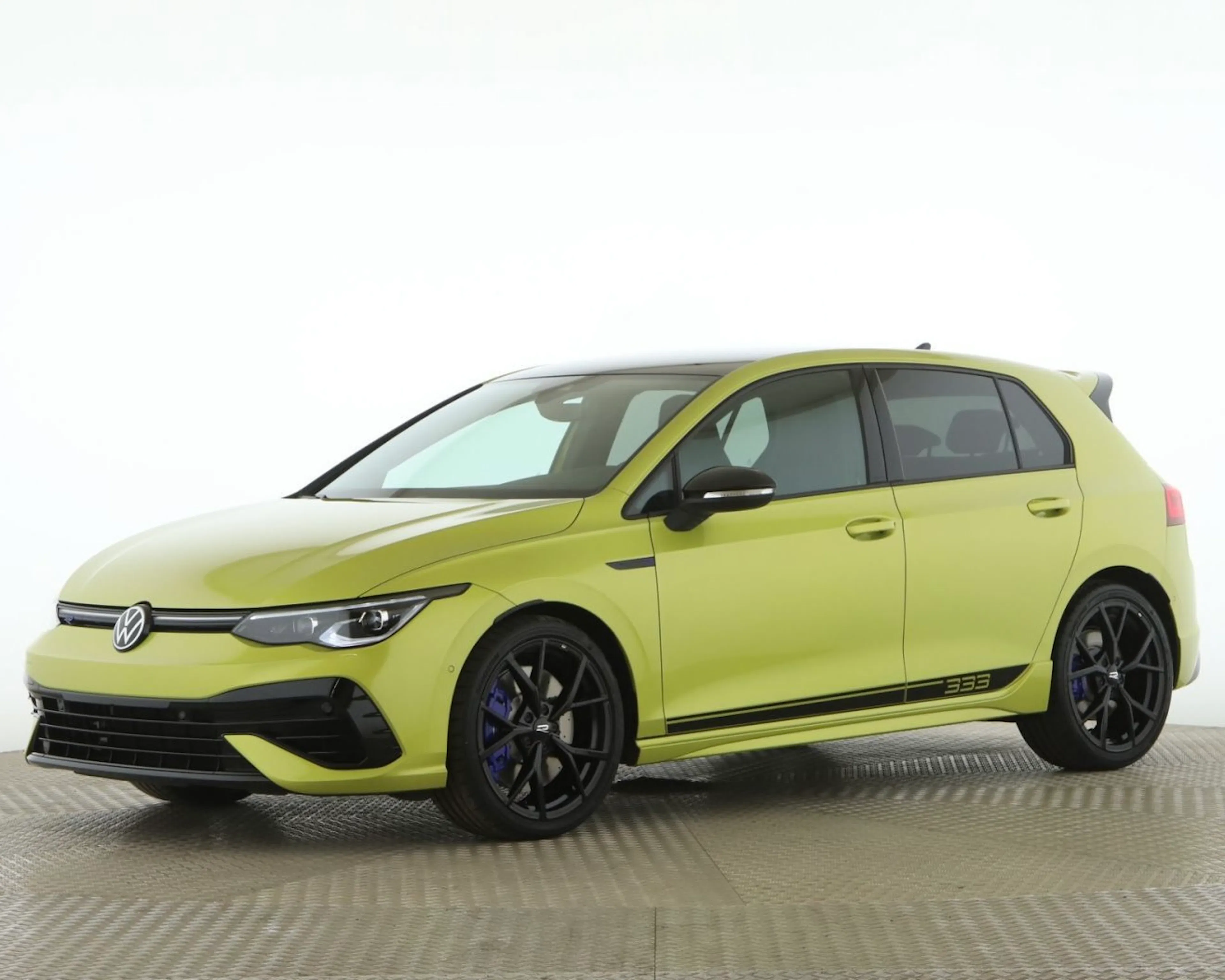 Gelber VW Golf mit schwarzen Akzenten, sportlicher Optik und schwarzen Felgen, seitlich die Zahl „333“, fotografiert auf neutralem Hintergrund.