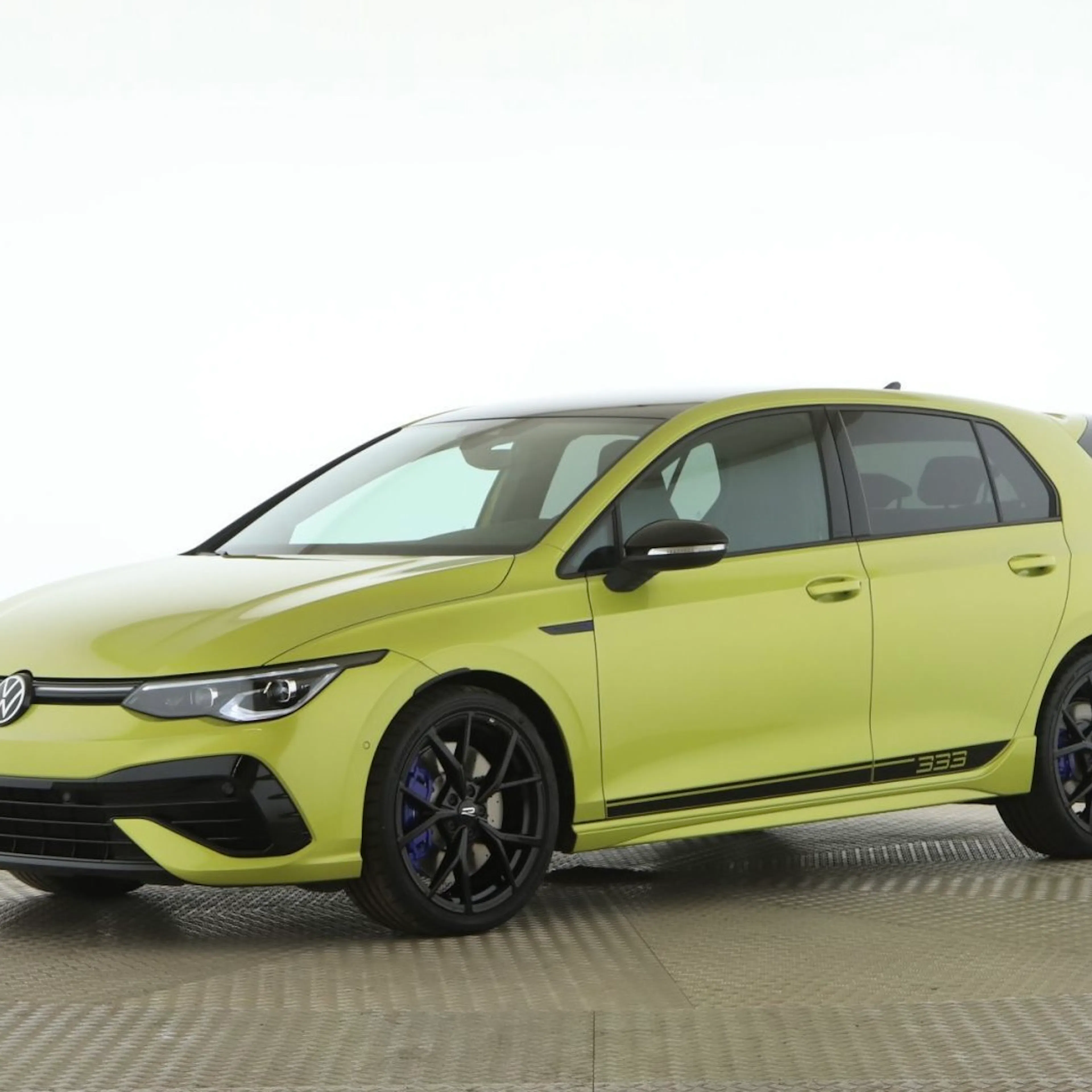 Gelber VW Golf mit schwarzen Akzenten, sportlicher Optik und schwarzen Felgen, seitlich die Zahl „333“, fotografiert auf neutralem Hintergrund.