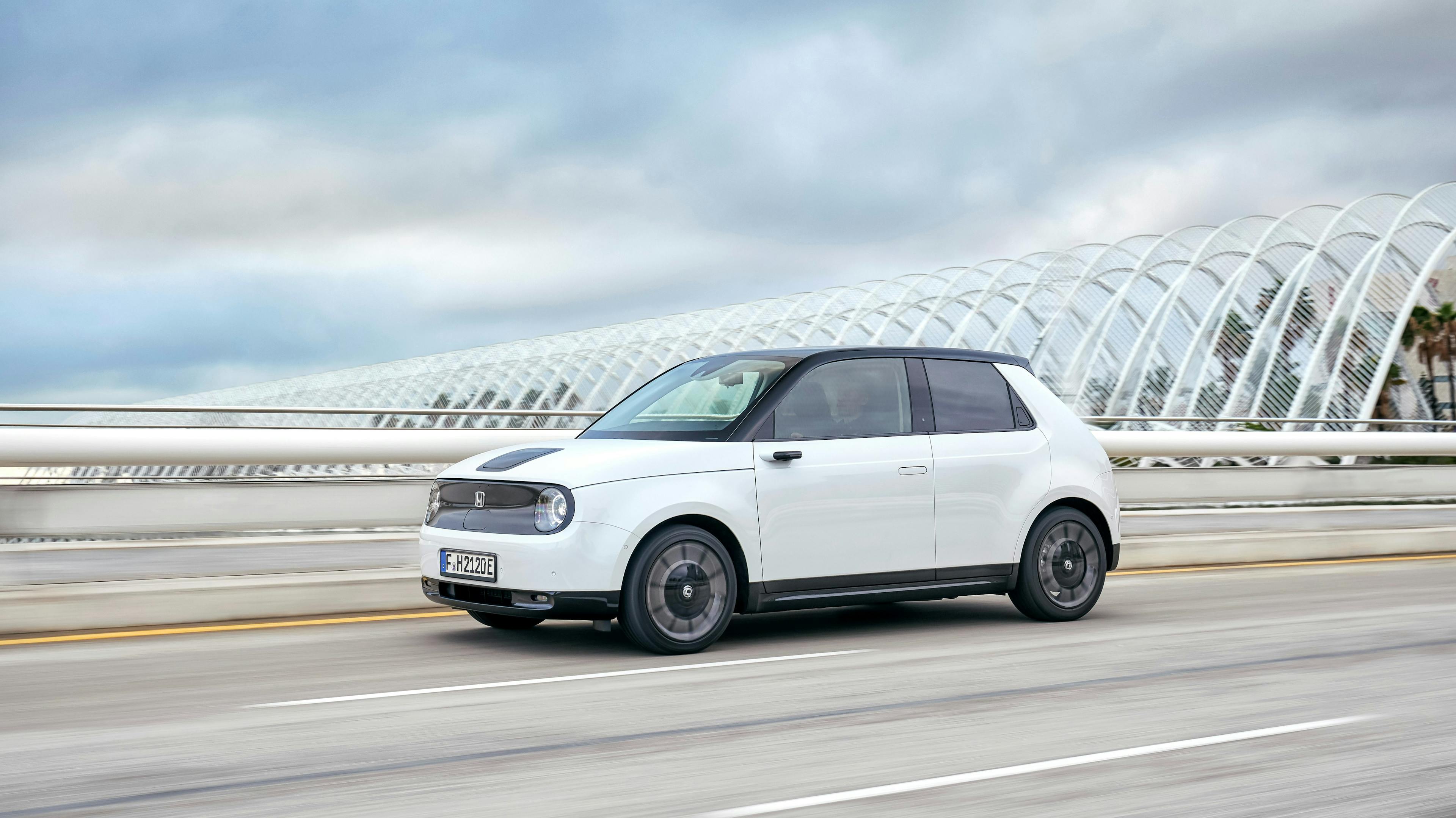 A white Honda e driving on a road