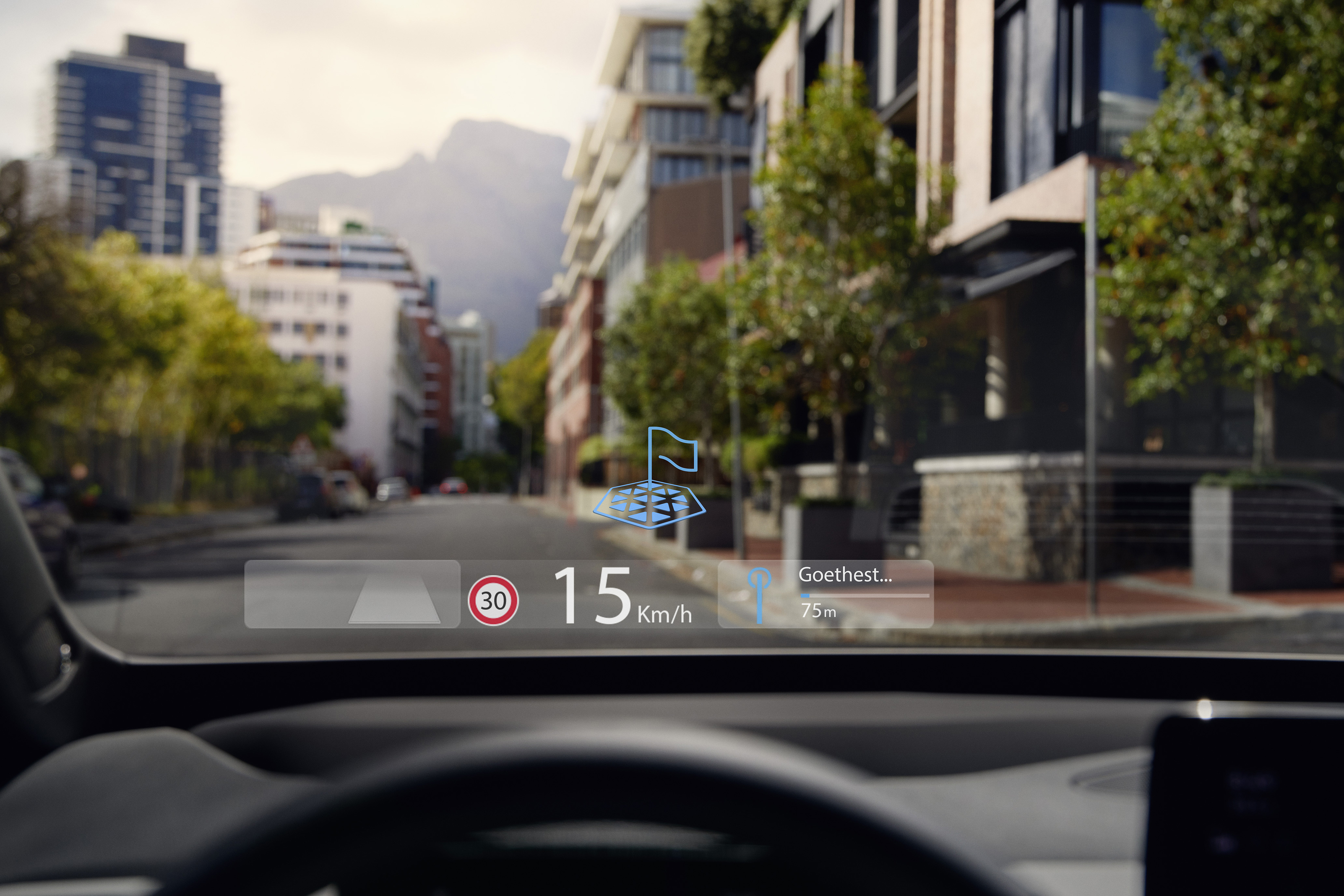 Auto-Head-up-Display zeigt Navigation und Tempolimit in Wohnstraße mit moderner Architektur und Bäumen. Berge im Hintergrund.