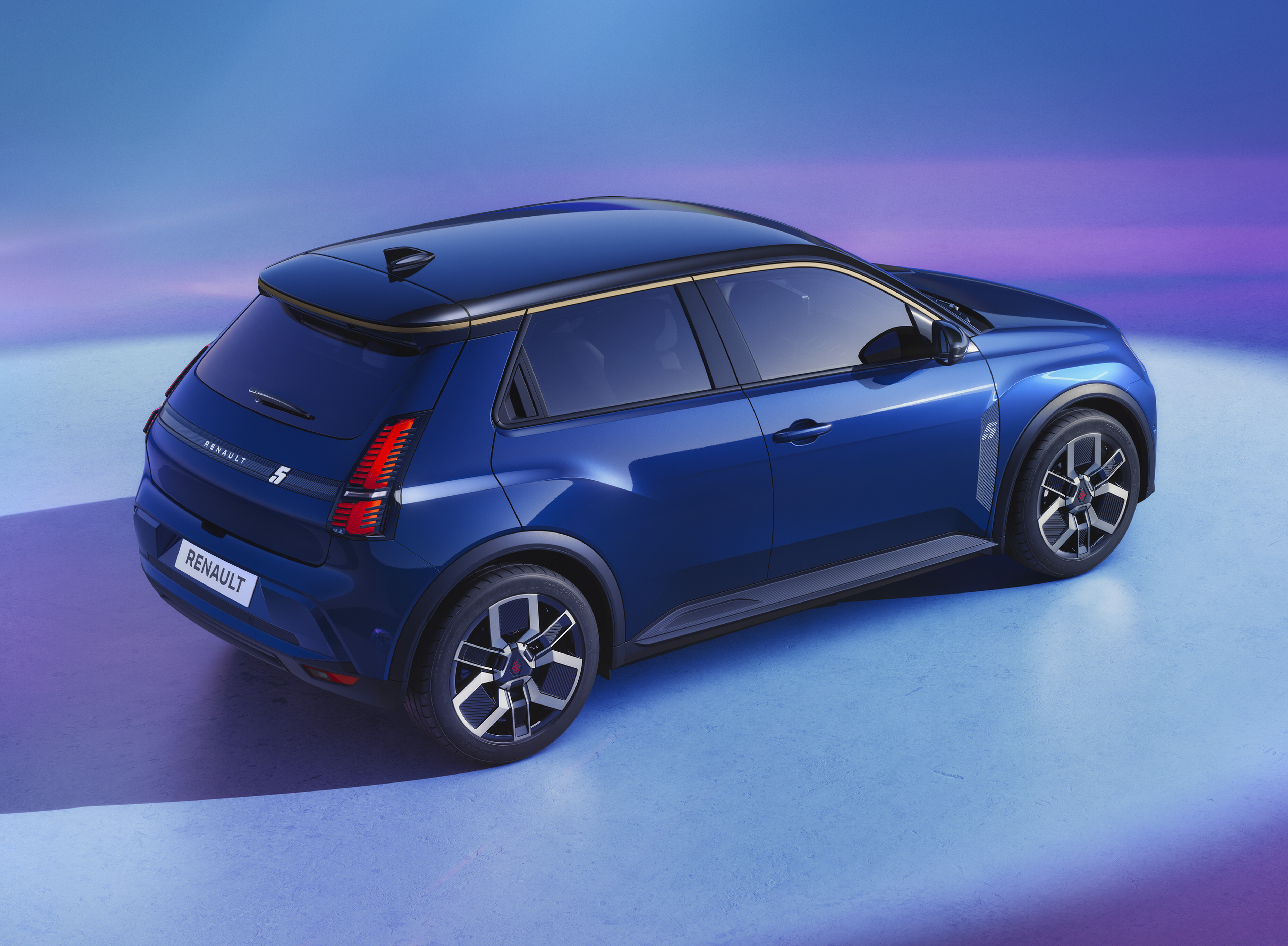 A blue Renault 5 E-Tech stands on a blue surface