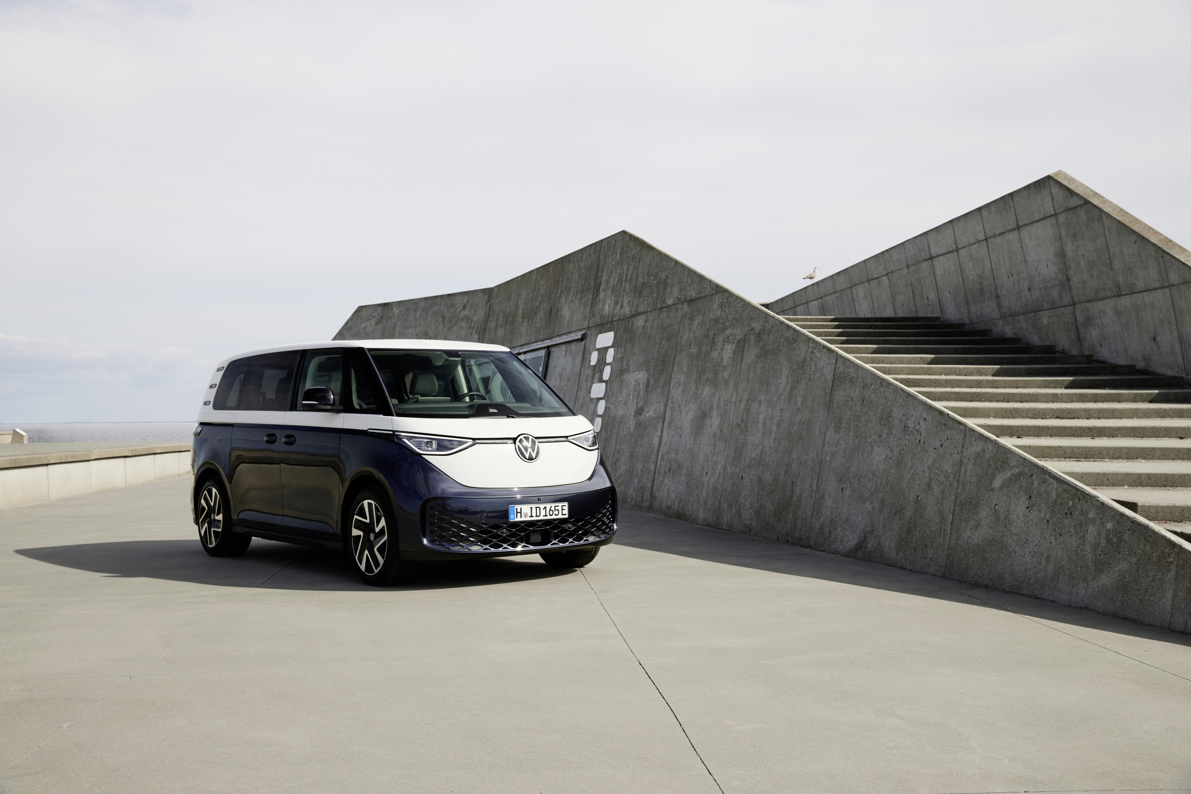 Ein blau-weißer VW ID. Buzz steht neben einer Treppe