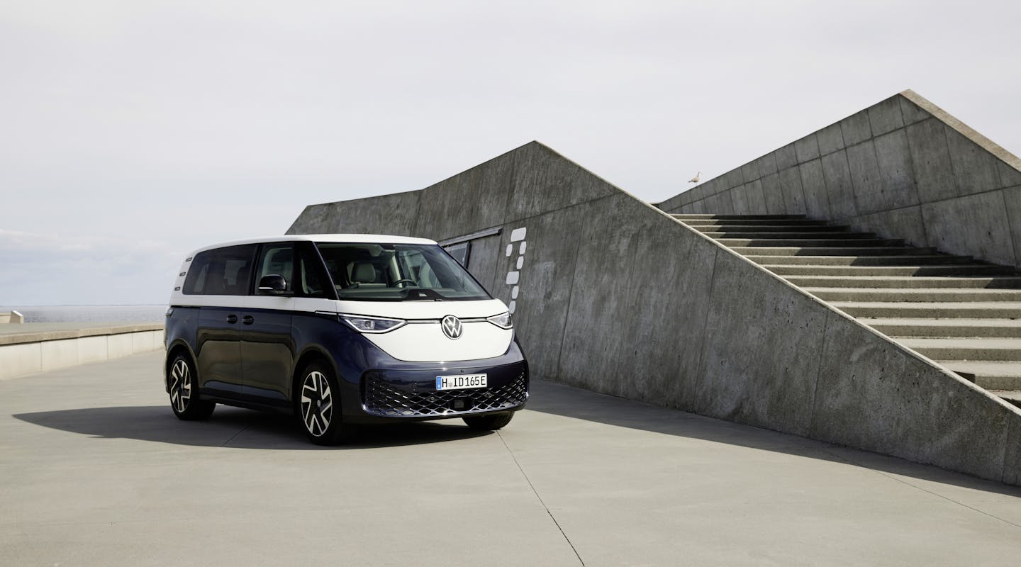 Ein blau-weißer VW ID. Buzz steht neben einer Treppe