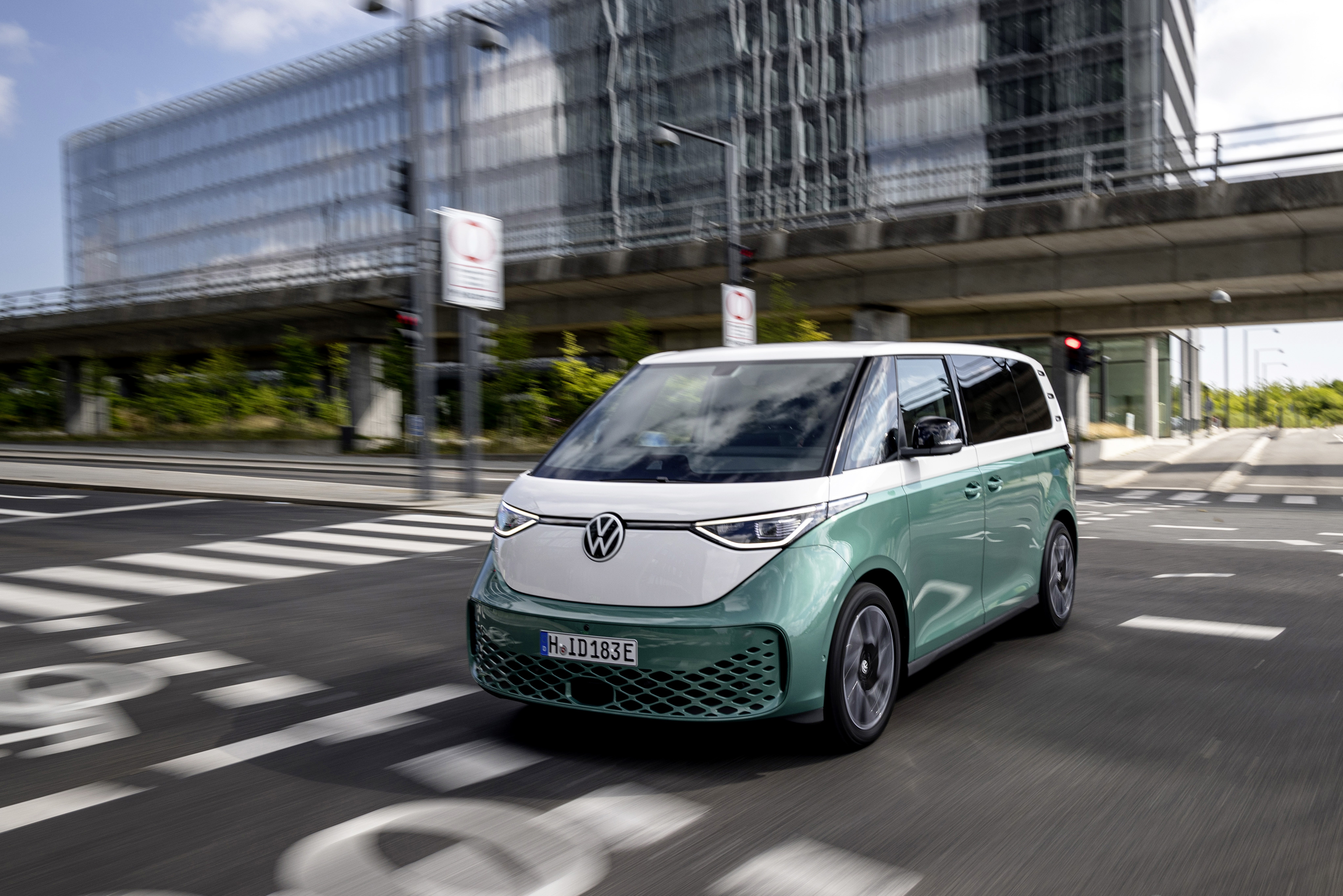 Ein grün-weißer VW ID. Buzz fährt durch eine Stadt