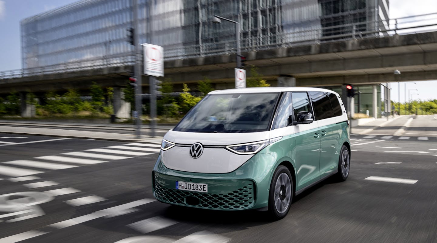 Ein grün-weißer VW ID. Buzz fährt durch eine Stadt