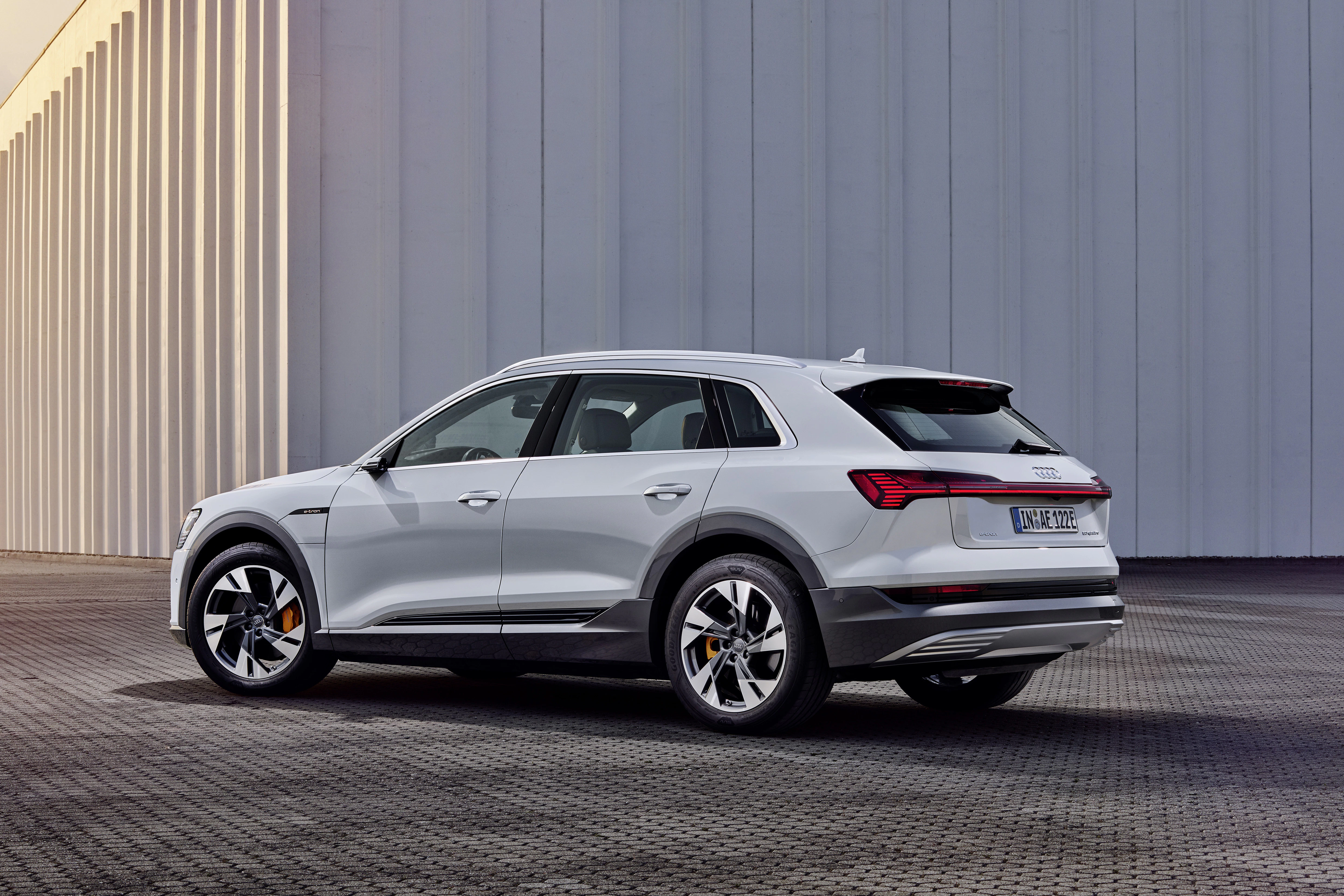 Ein grauer Audi e-tron steht vor einer Halle