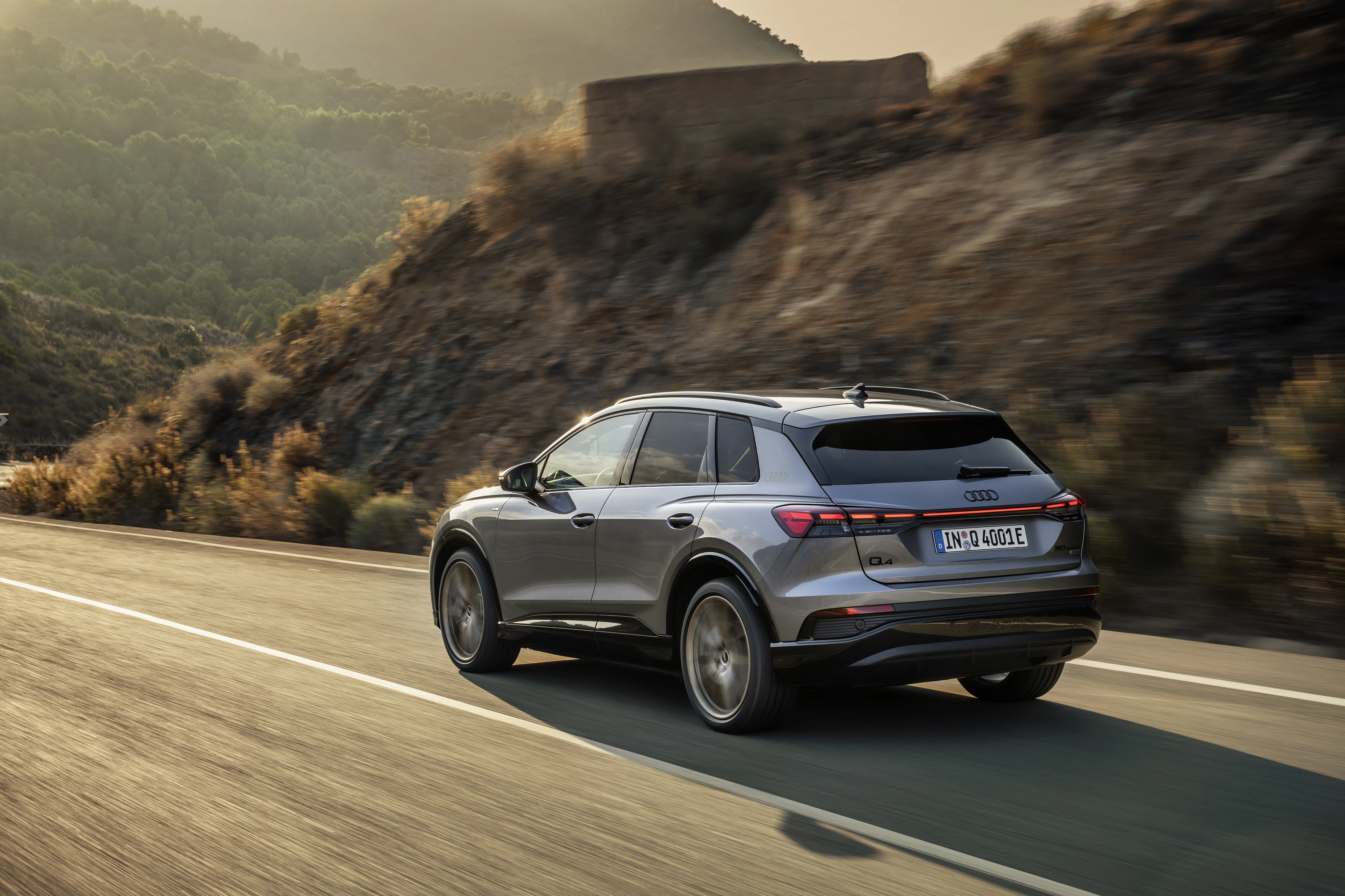Ein grauer Audi Q4 e-tron fährt auf einer Landstraße 