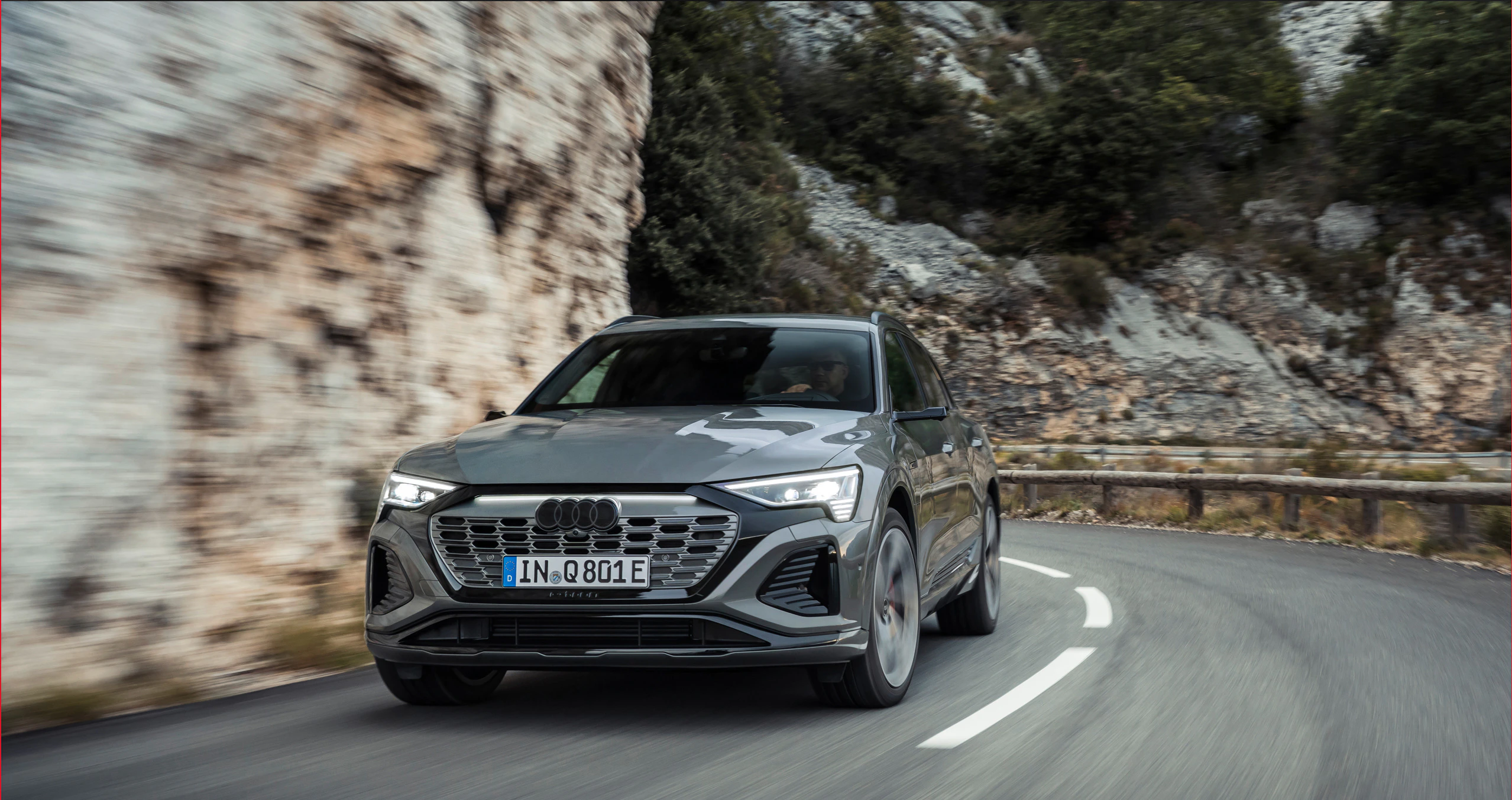 Ein grauer Audi Q8 e-tron fährt um eine Kurve 