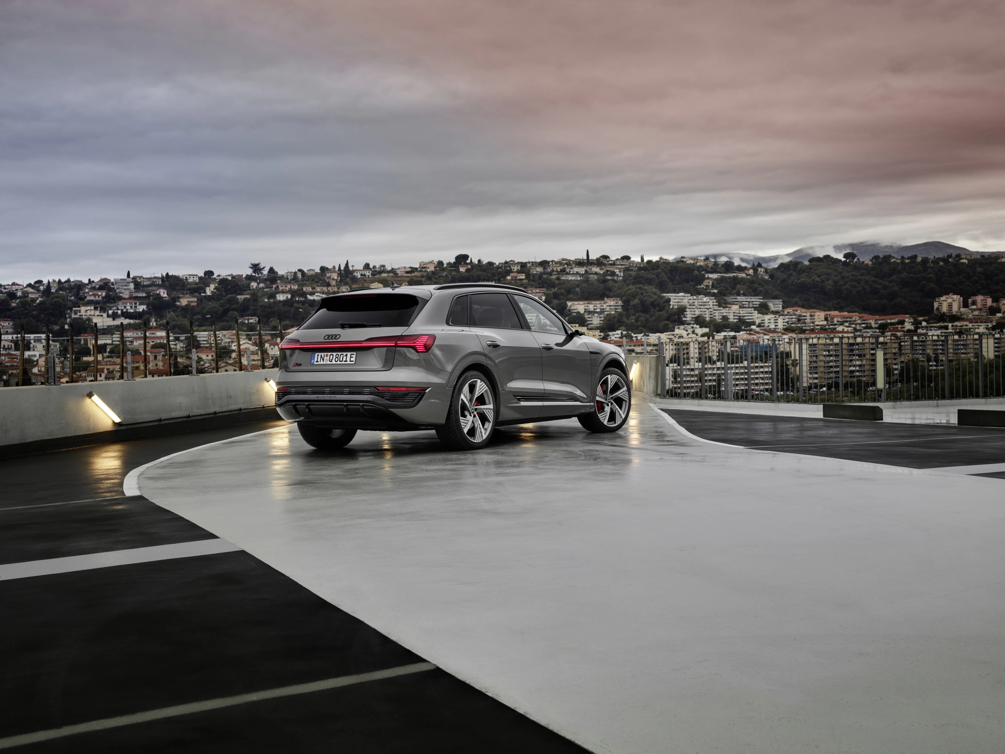 Ein grauer Audi Q8 e-tron parkt vor einen Stadt im Hintergrund