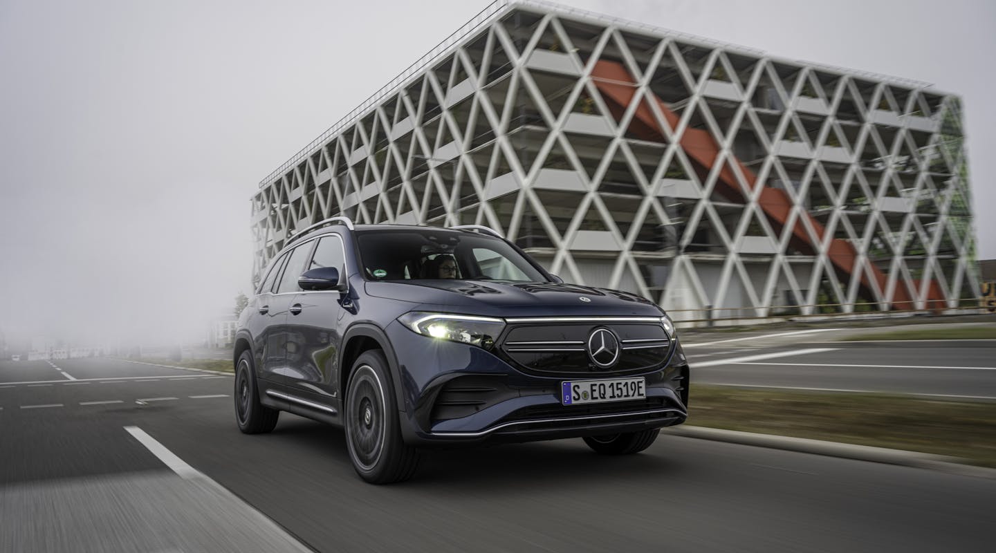 Ein blauer Mercedes-Benz EQB fährt vor einem Gebäude