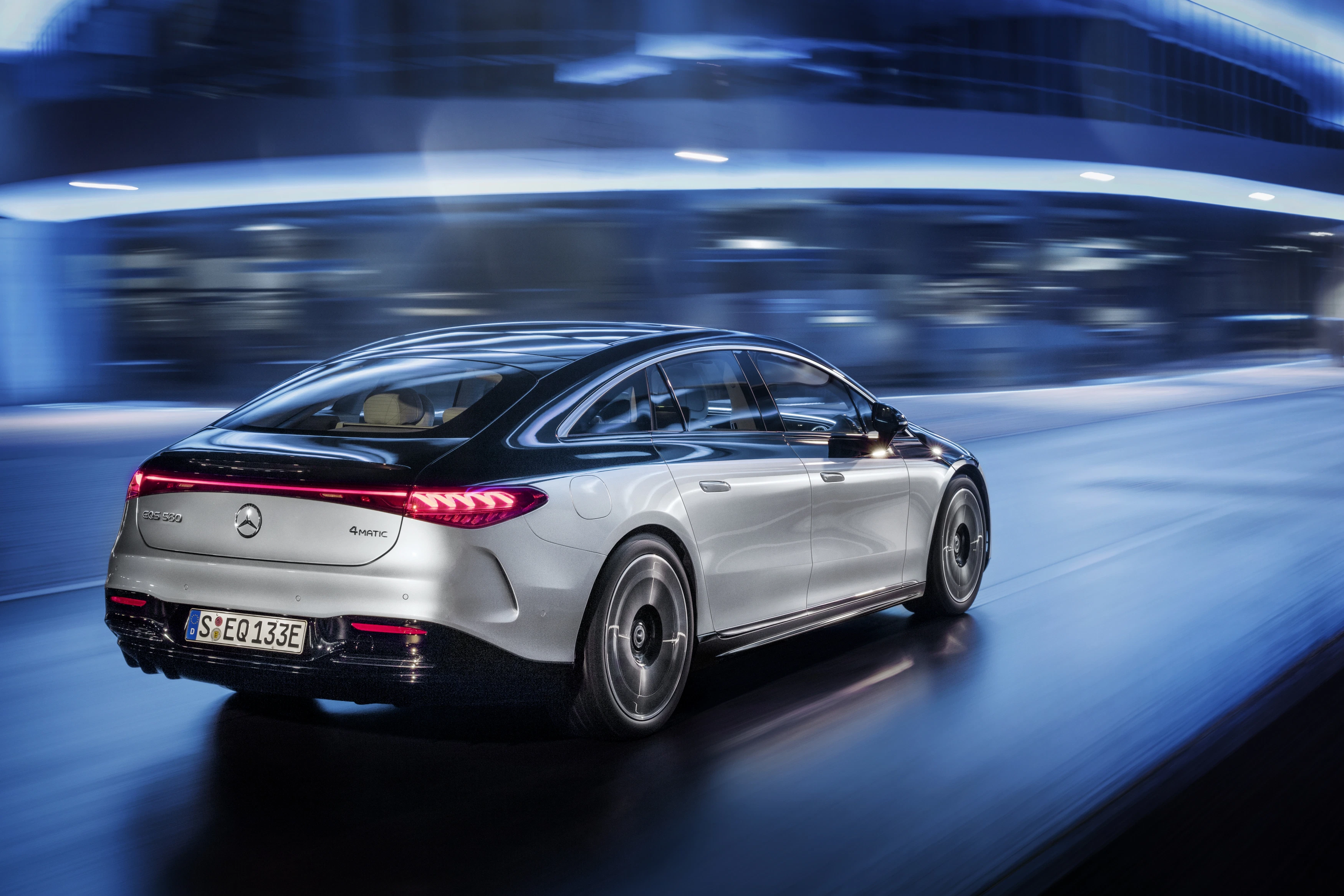 Das Heck von einem fahrenden Mercedes-Benz EQS in futuristischer Szenerie