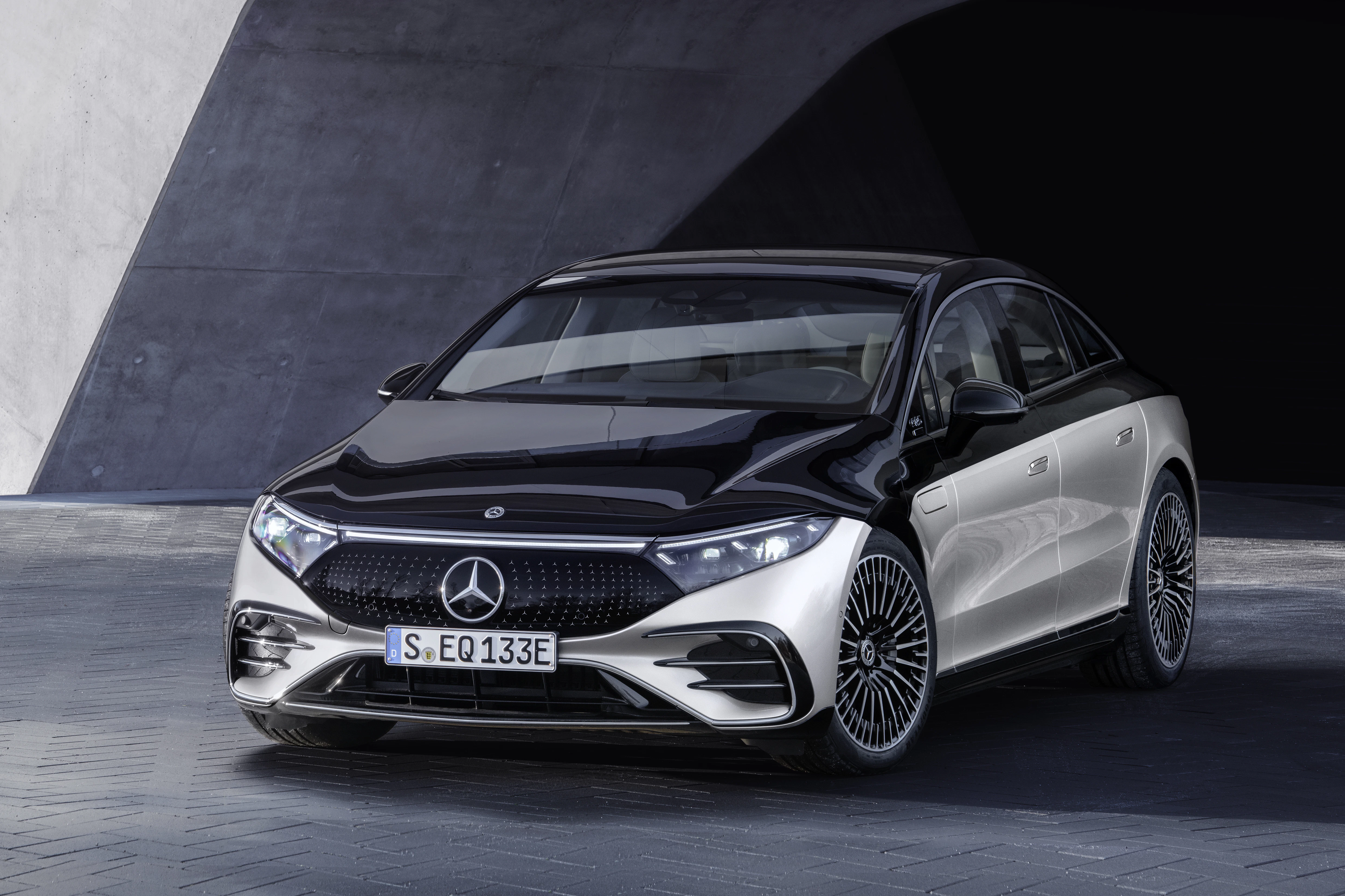 Ein grau-schwarzer Mercedes-Benz EQS steht vor einem Gebäude