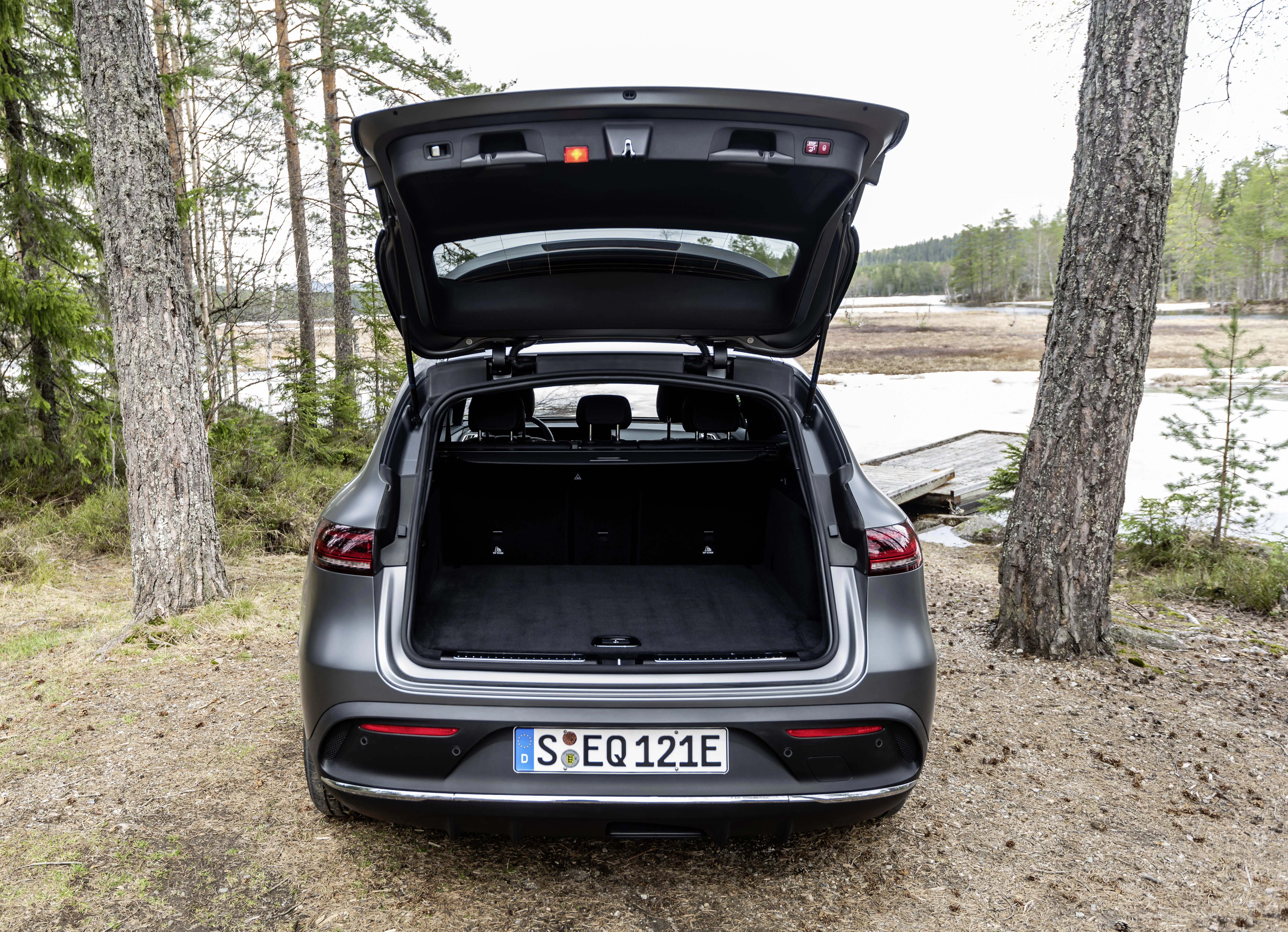 Ein Mercedes-Benz EQC steht mit offenem Kofferaum im Wald