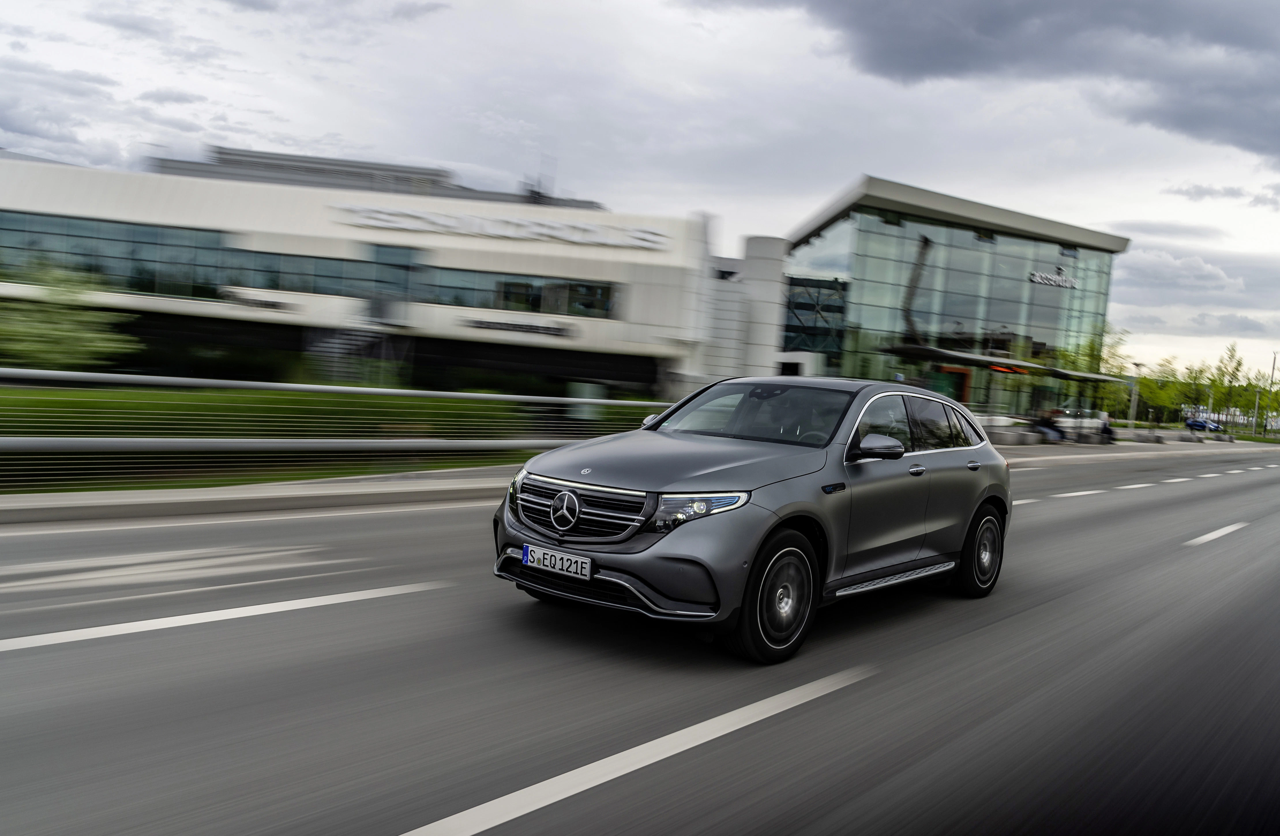 Ein grauer Mercedes-Benz EQC fährt an einem Gebäude vorbei