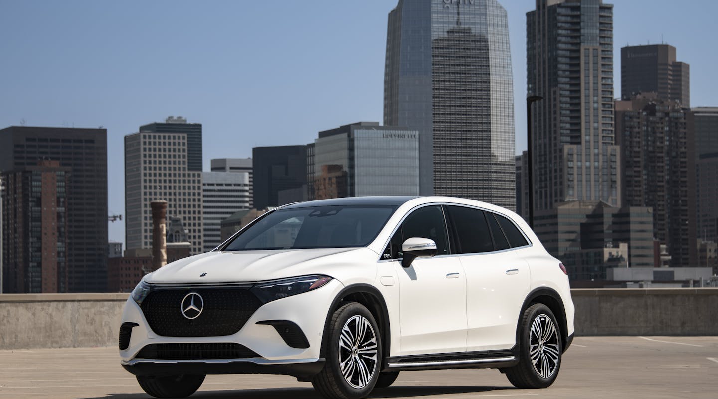 Ein weißer Mercedes-Benz EQS SUV steht vor einer Stadt